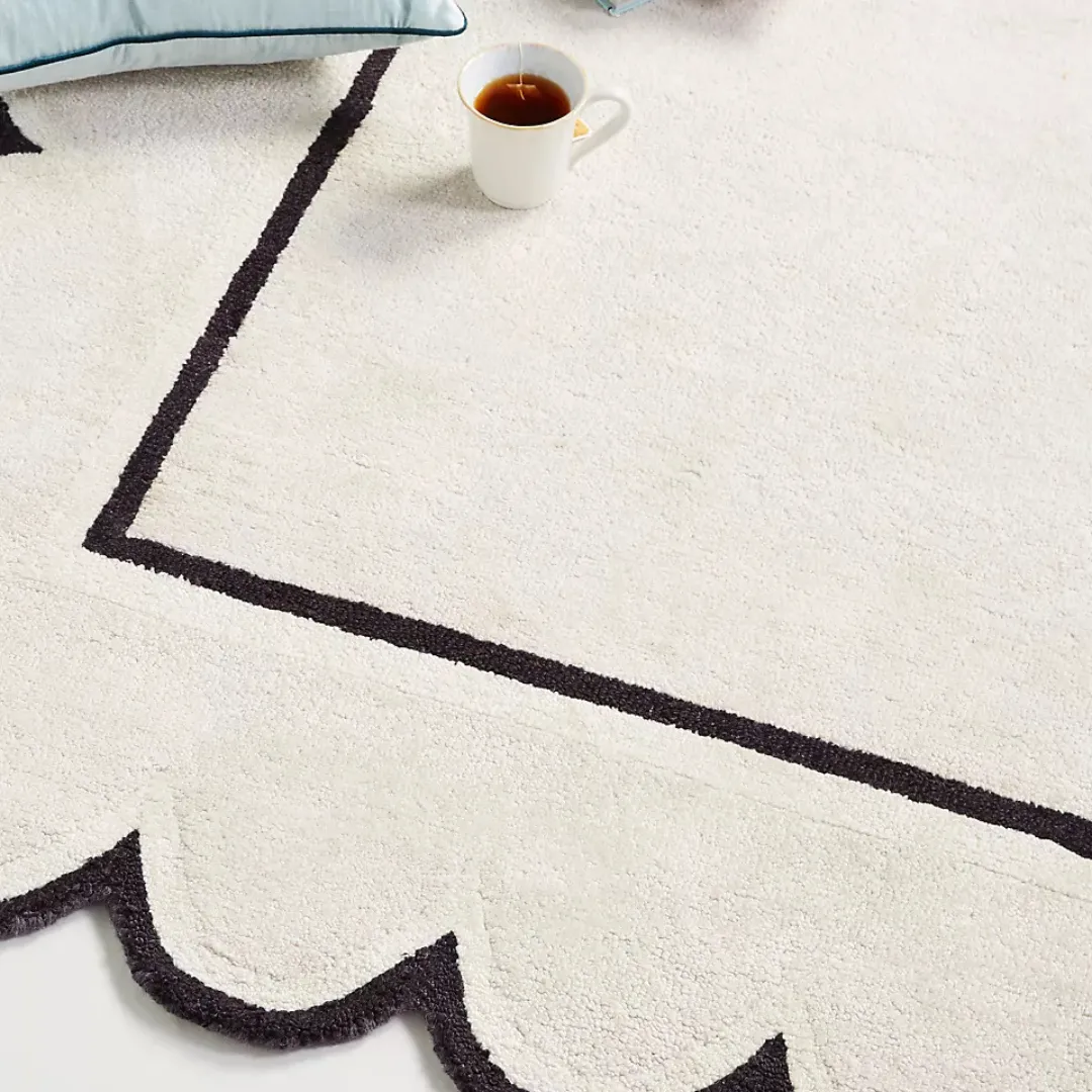 Detailed view of scalloped black edging on ivory tufted wool rug