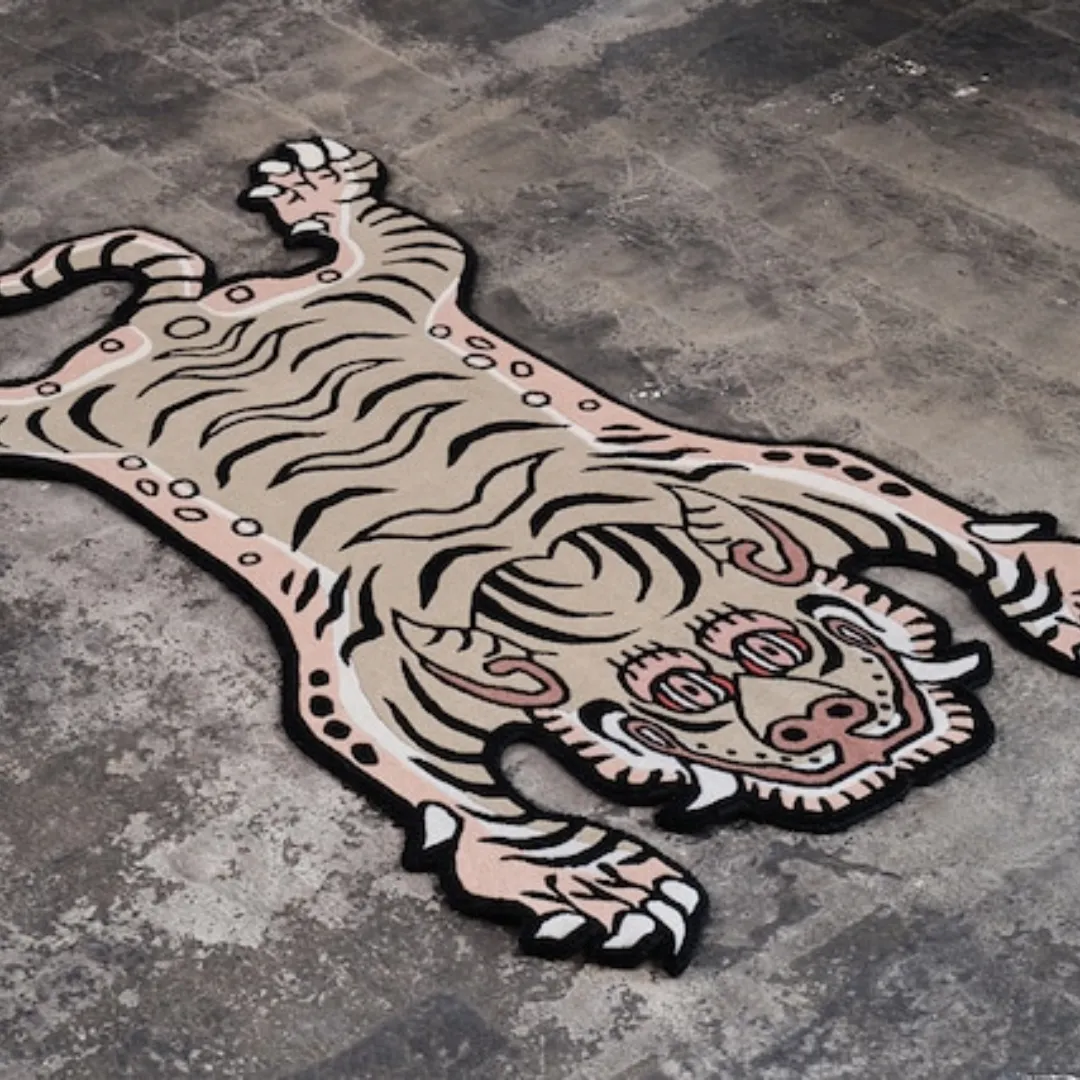 Cream saber tiger rug with striped body, smiling face, and sharp teeth, inspired by Tibetan tiger rug design.