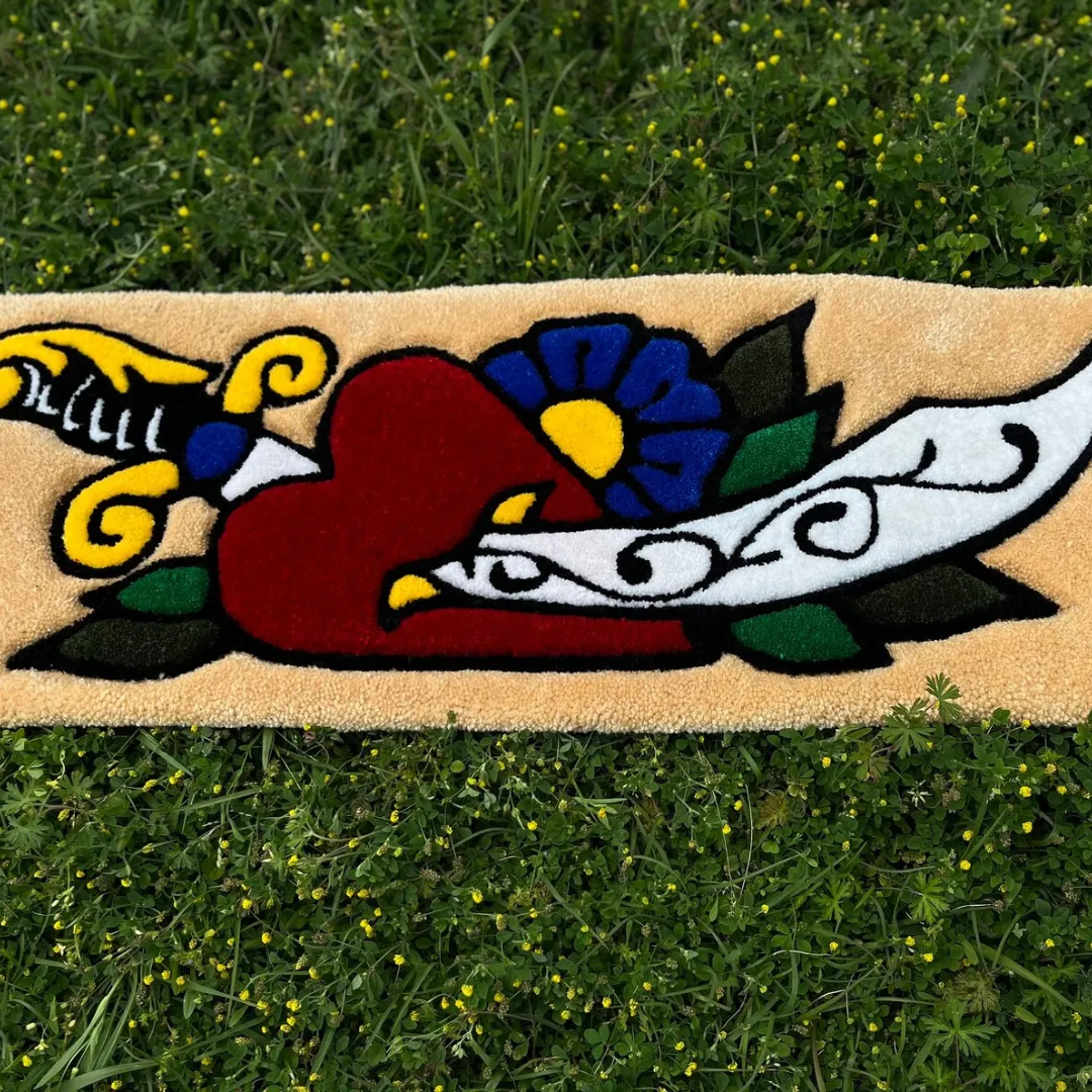 Handmade rug with a red heart, dagger, flower, and banner in classic inked flash art style