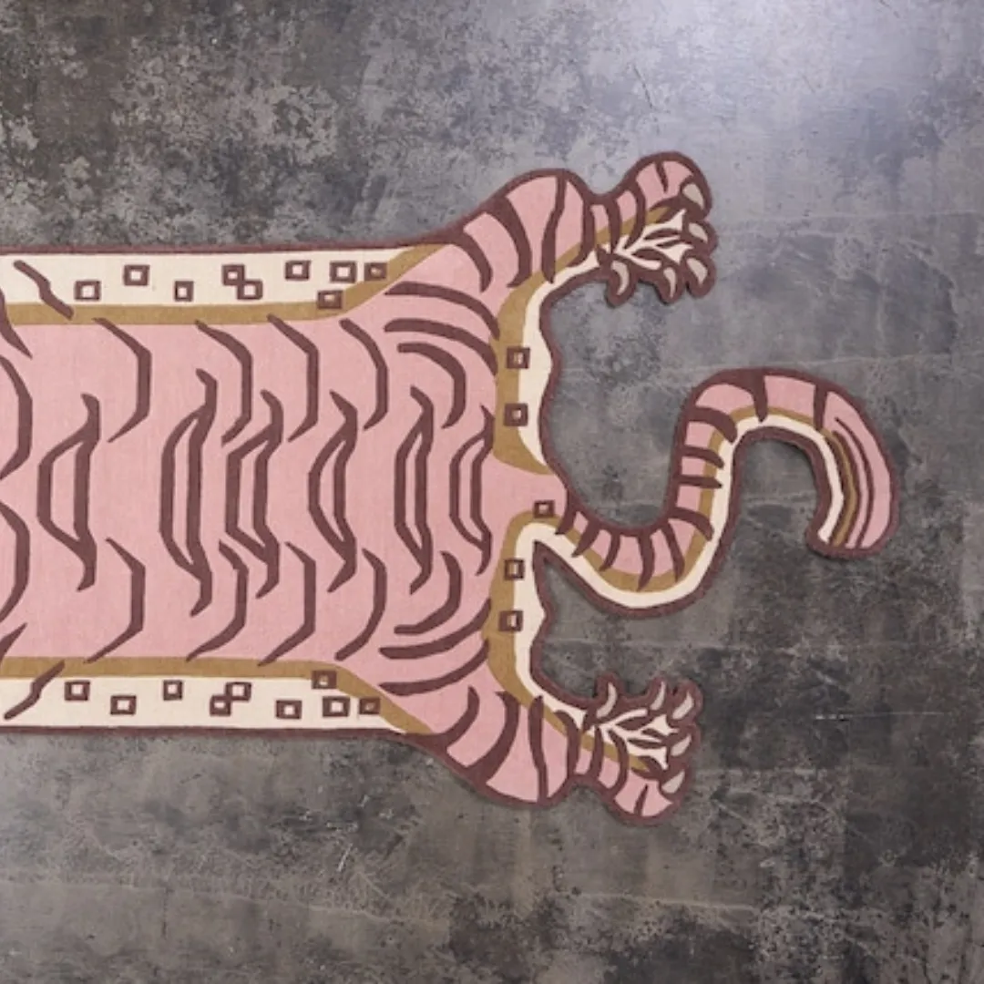 Hand tufted pink tiger rug featuring traditional Tibetan design and playful cartoon-like facial details.