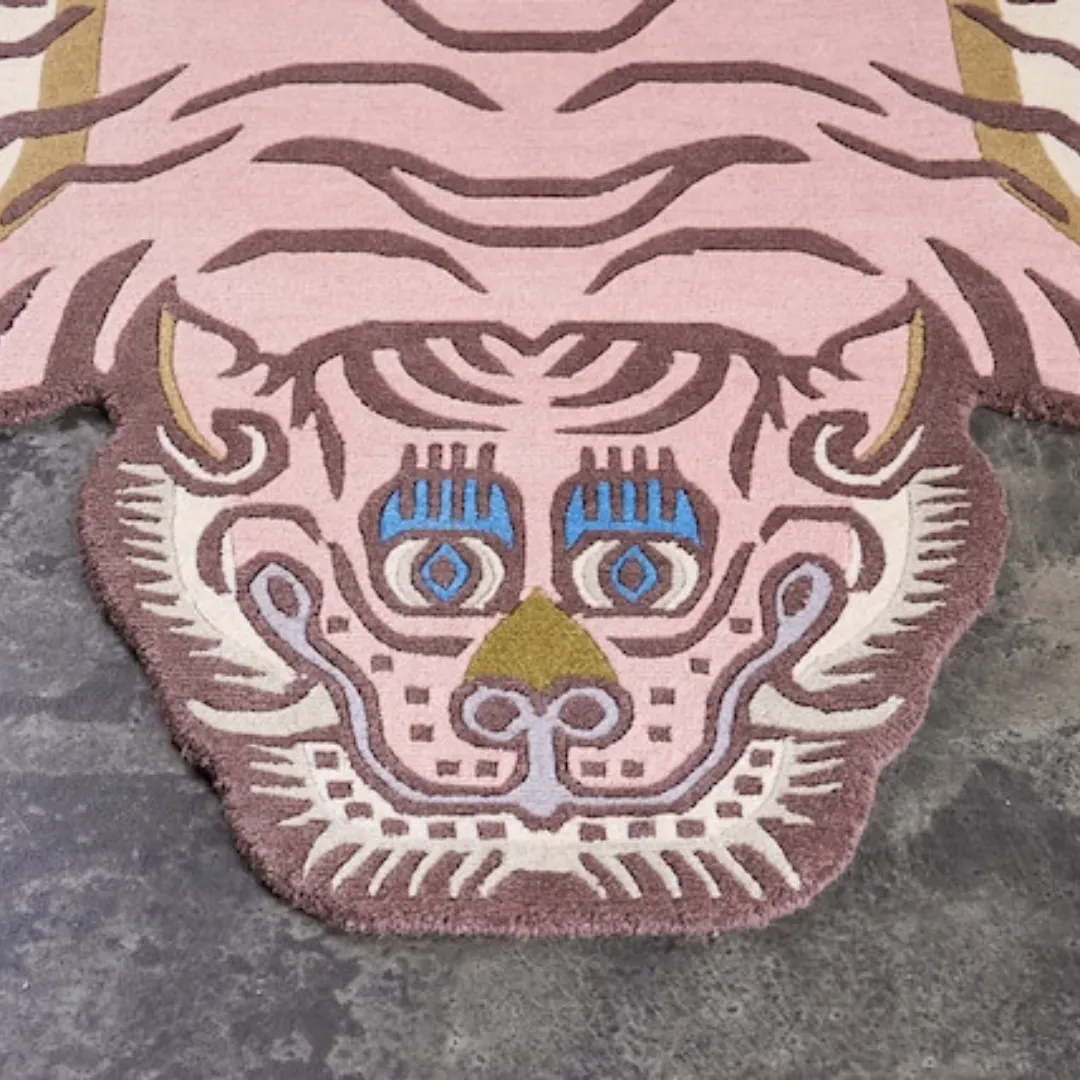 Tibetan-style tiger rug in soft pink with curved stripes and blue eyes, handcrafted from 100% wool.