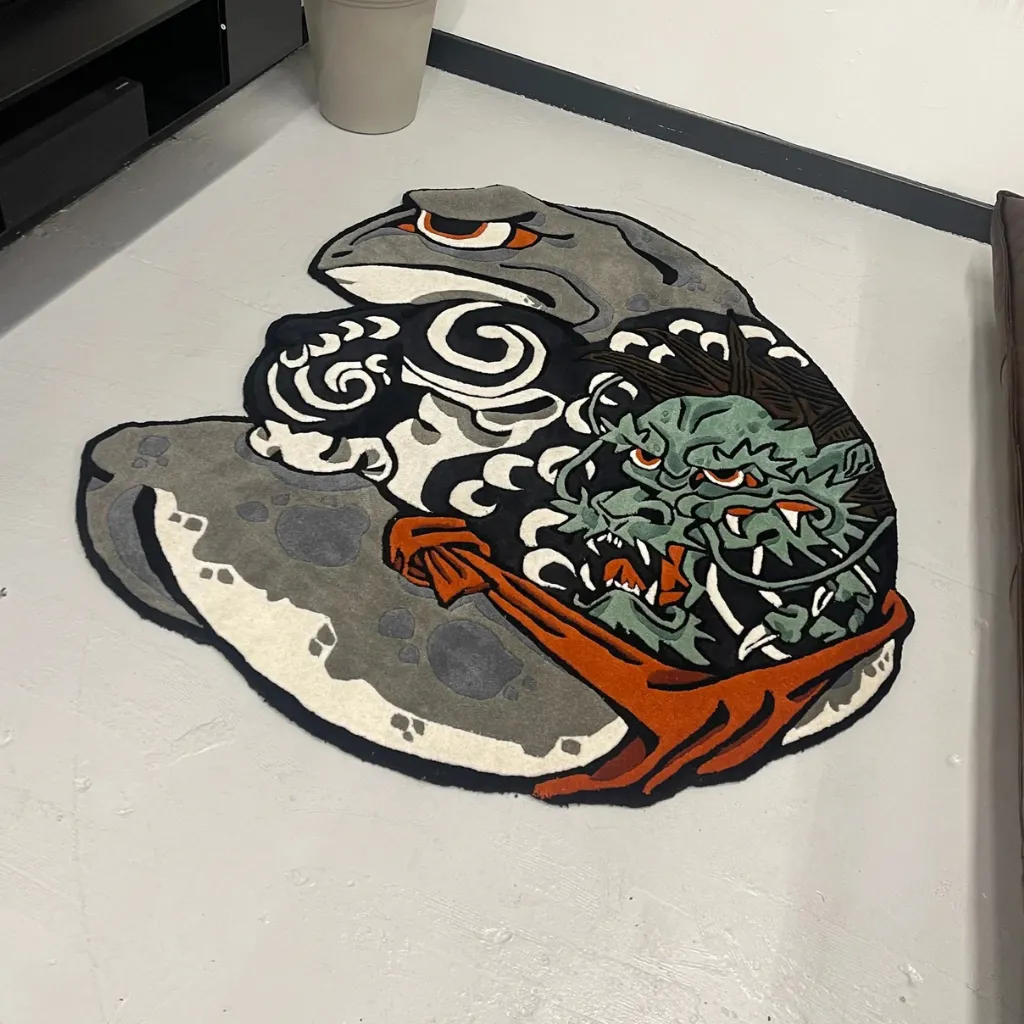 kaeru musashi hand tufted wool rug design Angled view of the Kaeru Musashi rug on a grey floor, showcasing the custom die-cut shape and the intricate details of the battle scene between the toad and dragon.