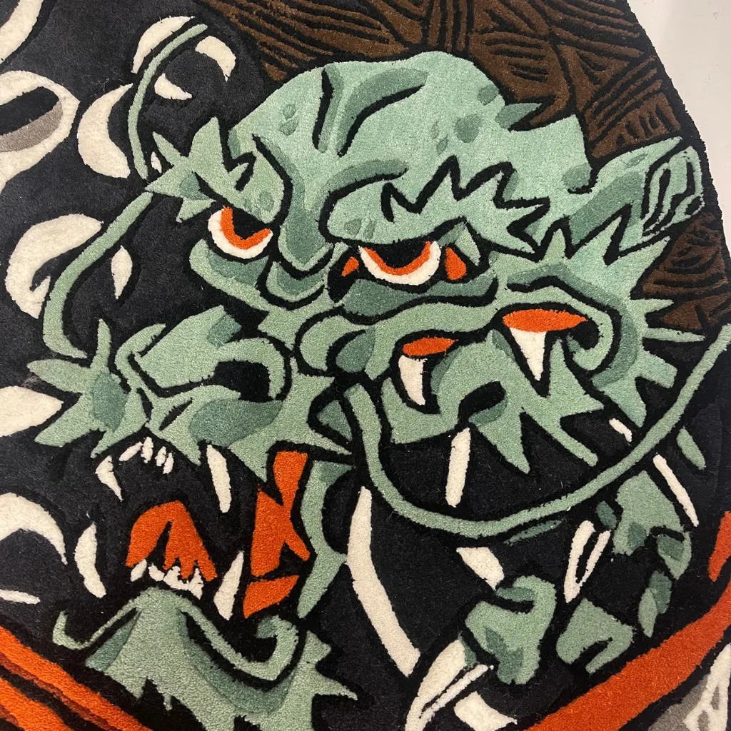 kaeru musashi rug texture detail dragon close up Extreme close-up of the Kaeru Musashi rug, highlighting the dense hand-tufted wool pile, carved 3D texture, and vibrant colors of the green dragon's face and orange accents.