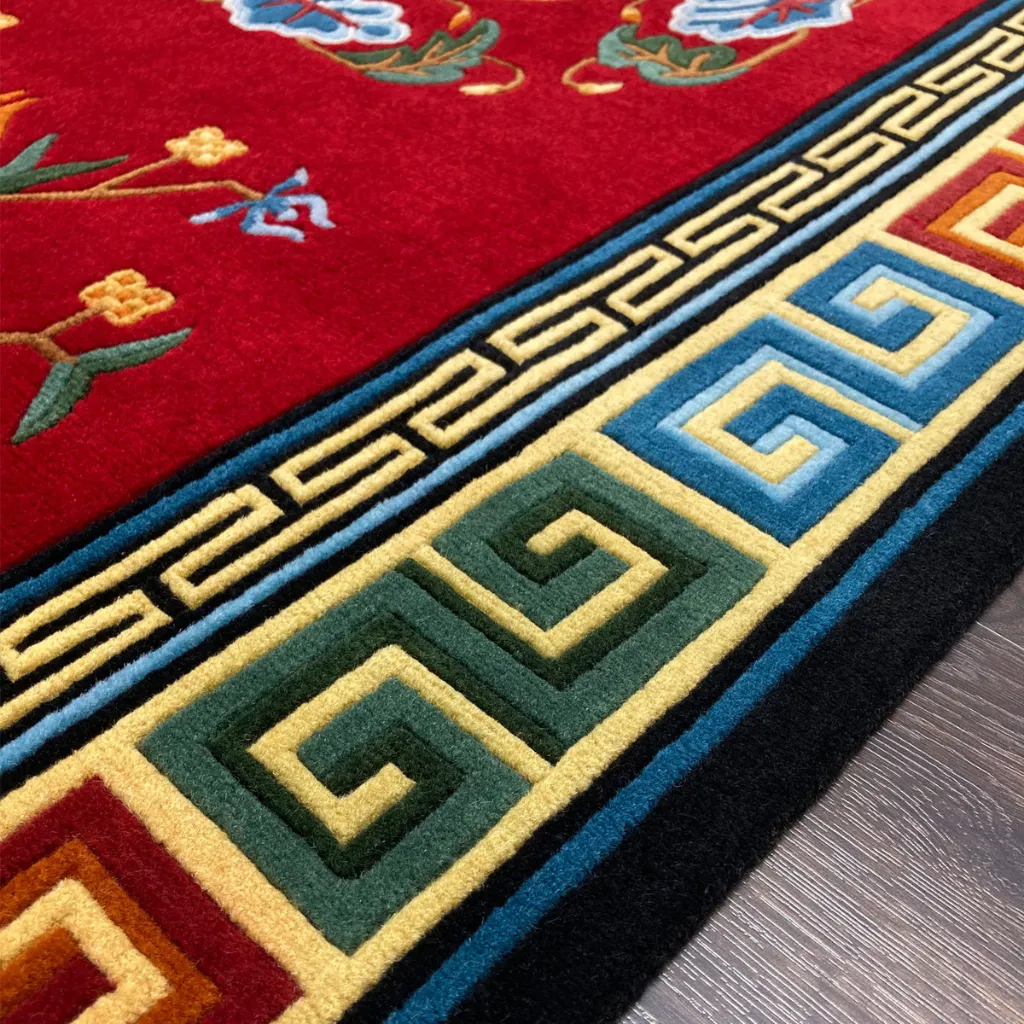 lotus throne rug greek key border detail Extreme close up detail of the Lotus Throne rug highlighting the dense plush wool pile and the precise carving of the blue and yellow geometric greek key border.