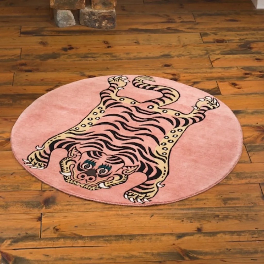 petal prawl round pink tiger animal rug Angled view of the Petal Prawl rug, highlighting the dense hand-tufted wool texture and the intricate black wandering stripe pattern on a pastel pink field.