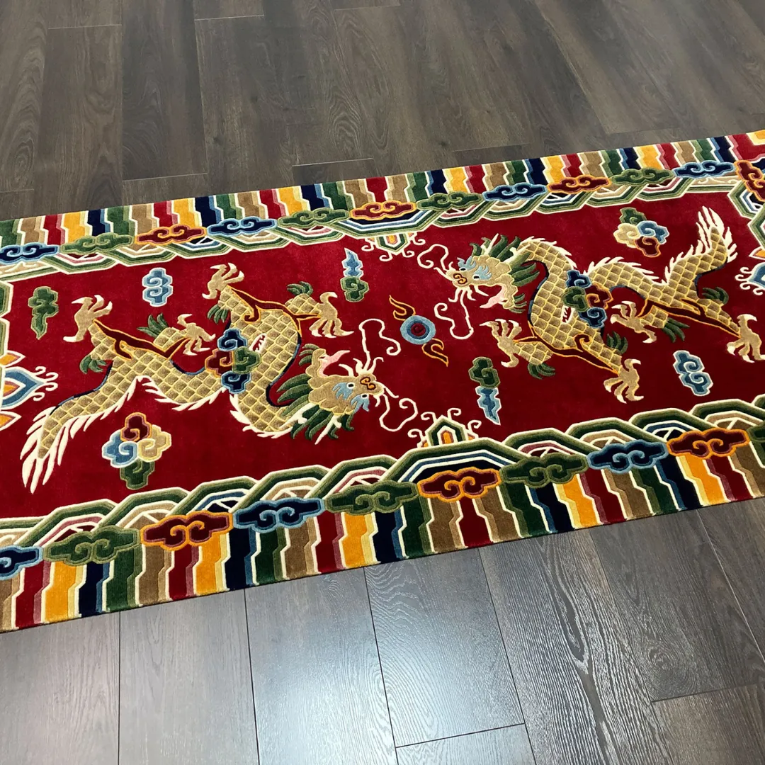 Sacred Triumph Red Wool Area Rug High angle shot of the rectangular Sacred Triumph rug on a dark wood floor, displaying the vibrant red color and intricate oriental dragon motifs.