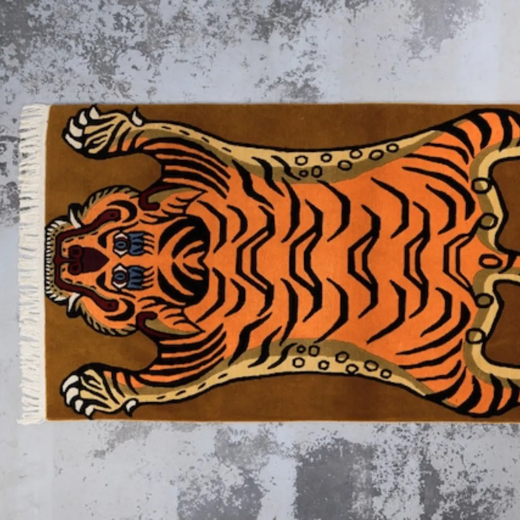 sunstripe roar mustard tiger skin shaped rug wood floor High angle view of the full Sunstripe Roar rug placed on a rustic wooden floor, showcasing the traditional Tibetan tiger skin shape in a vibrant mustard yellow and black colorway.