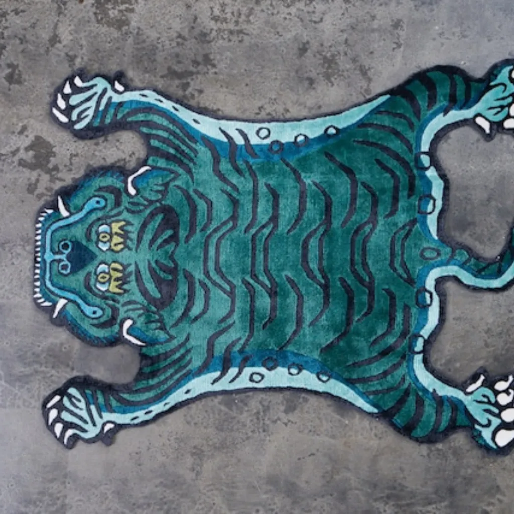 tidal prowl aqua tiger skin shaped rug wood floor High angle view of the full Tidal Prowl rug placed on a rustic wooden floor, showcasing the traditional Tibetan tiger skin shape reimagined in a vibrant aqua and black colorway.