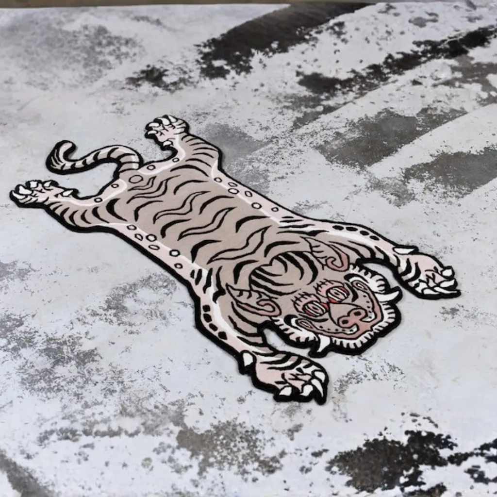 whispered paws hand tufted wool snow tiger rug design Angled view of the Whispered Paws rug, highlighting the dense hand-tufted wool texture and the high-contrast black striping on a pristine cream/white background.