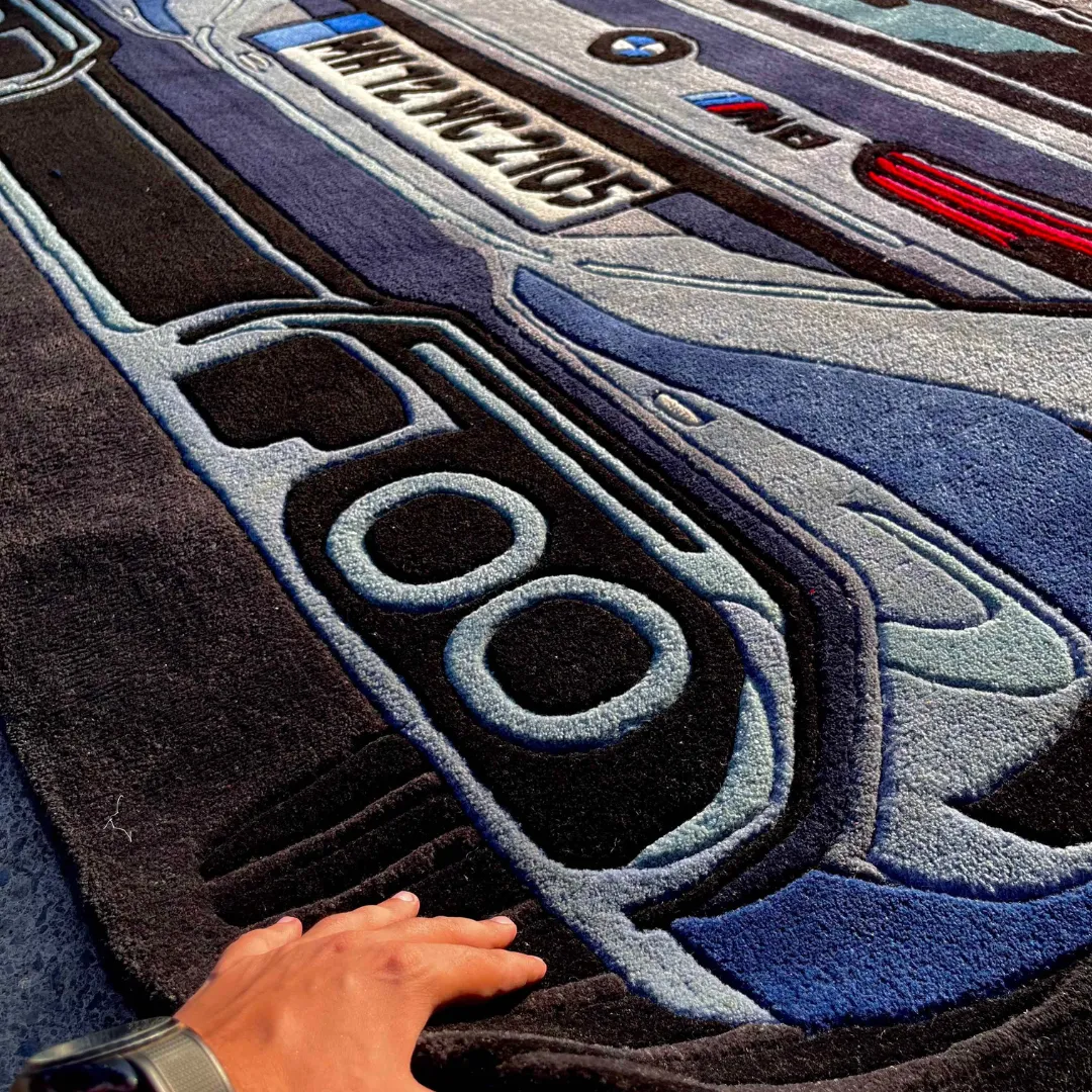 iron nomad bmw m8 rug texture Close-up angled view of the Iron Nomad rug, highlighting the plush hand-tufted wool texture of the quad exhaust pipes and the precise lettering of the license plate.