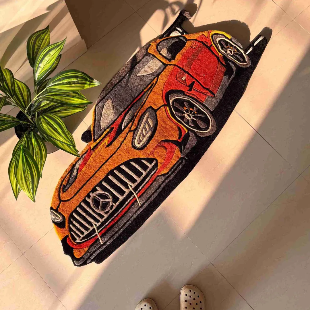 racing gold mercedes sports car rug Top down view of the Racing Gold rug featuring a custom die-cut design of a Mercedes-AMG style race car in vibrant orange, gold, and black hand-tufted wool.
