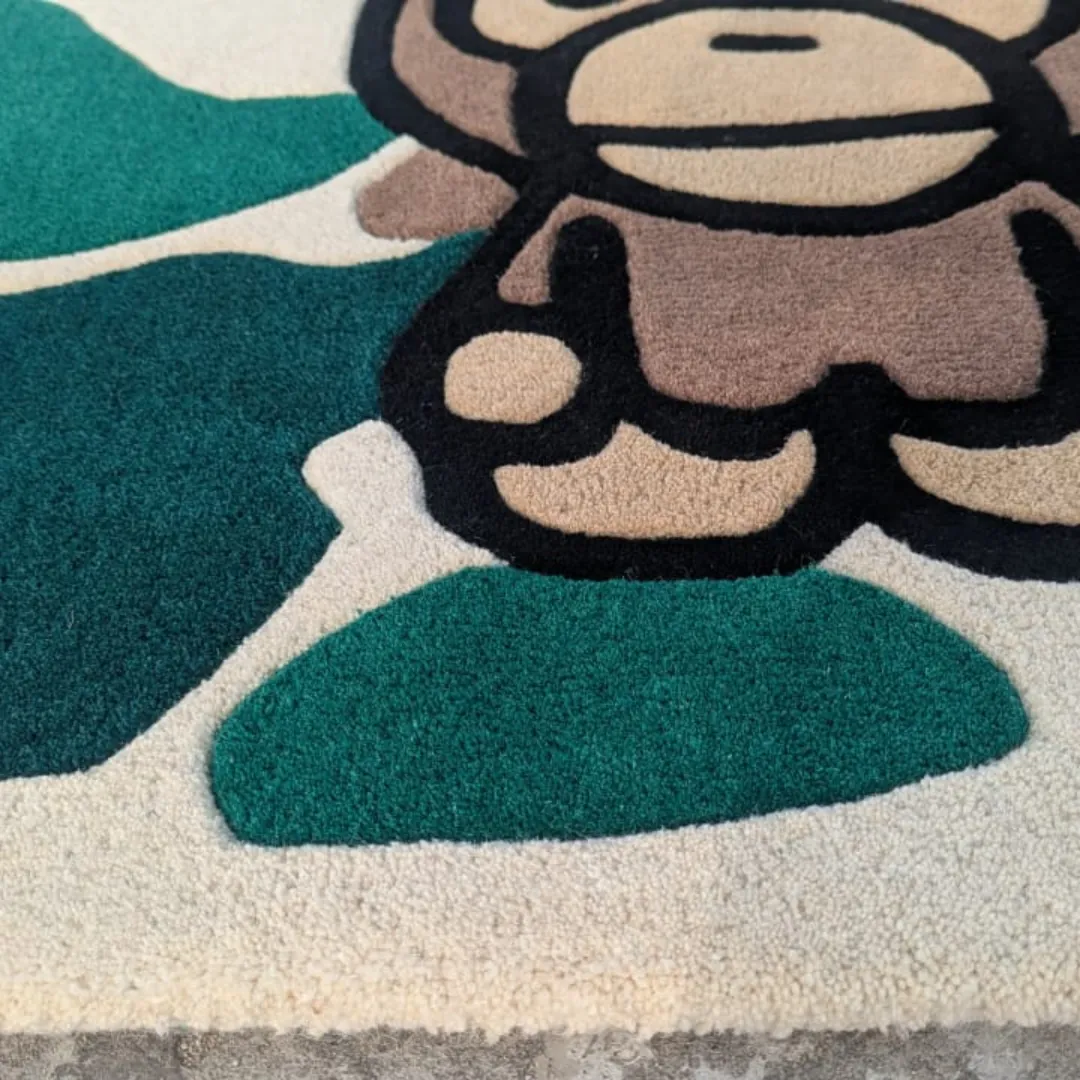Close-up texture detail of the Camo Heritage rug, emphasizing the dense, plush hand-tufted pile and the clean, black carved lines that outline the central ape character against the green and cream background.