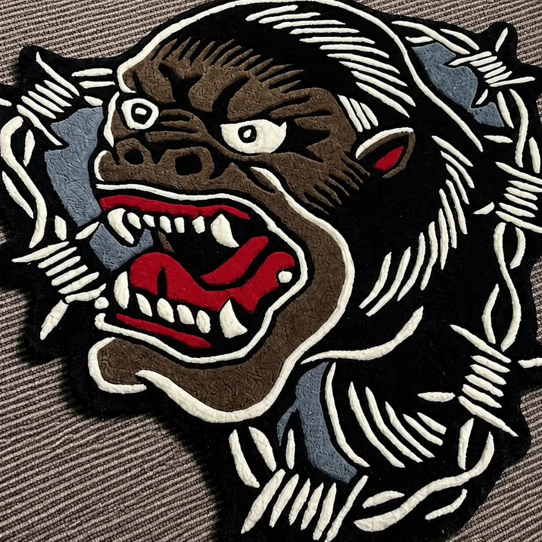 Close-up of the detailed tufted pile texture, sharp white fangs, roaring red mouth, and intricate barbed wire border on the King Kong rug.