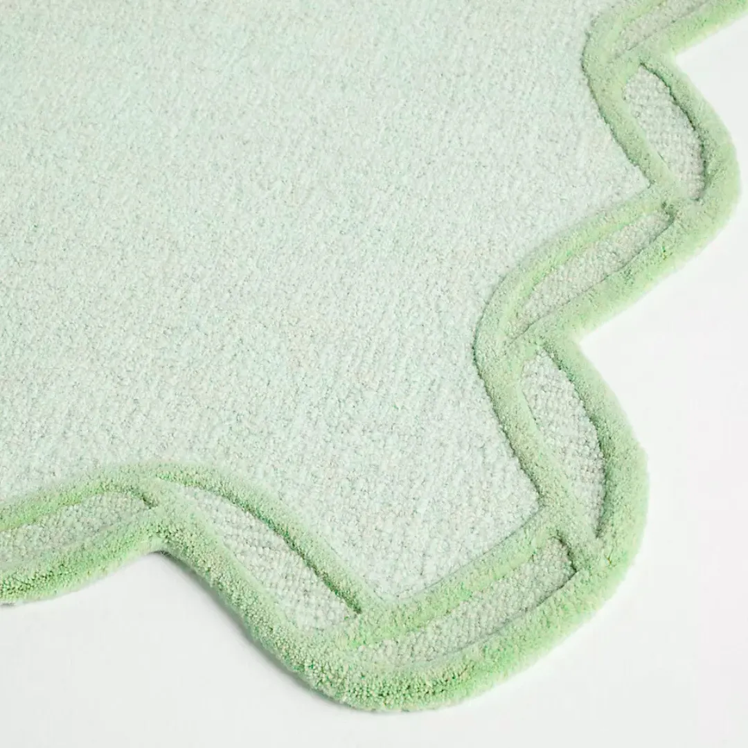 Close-up showing scalloped edges on green wool rug