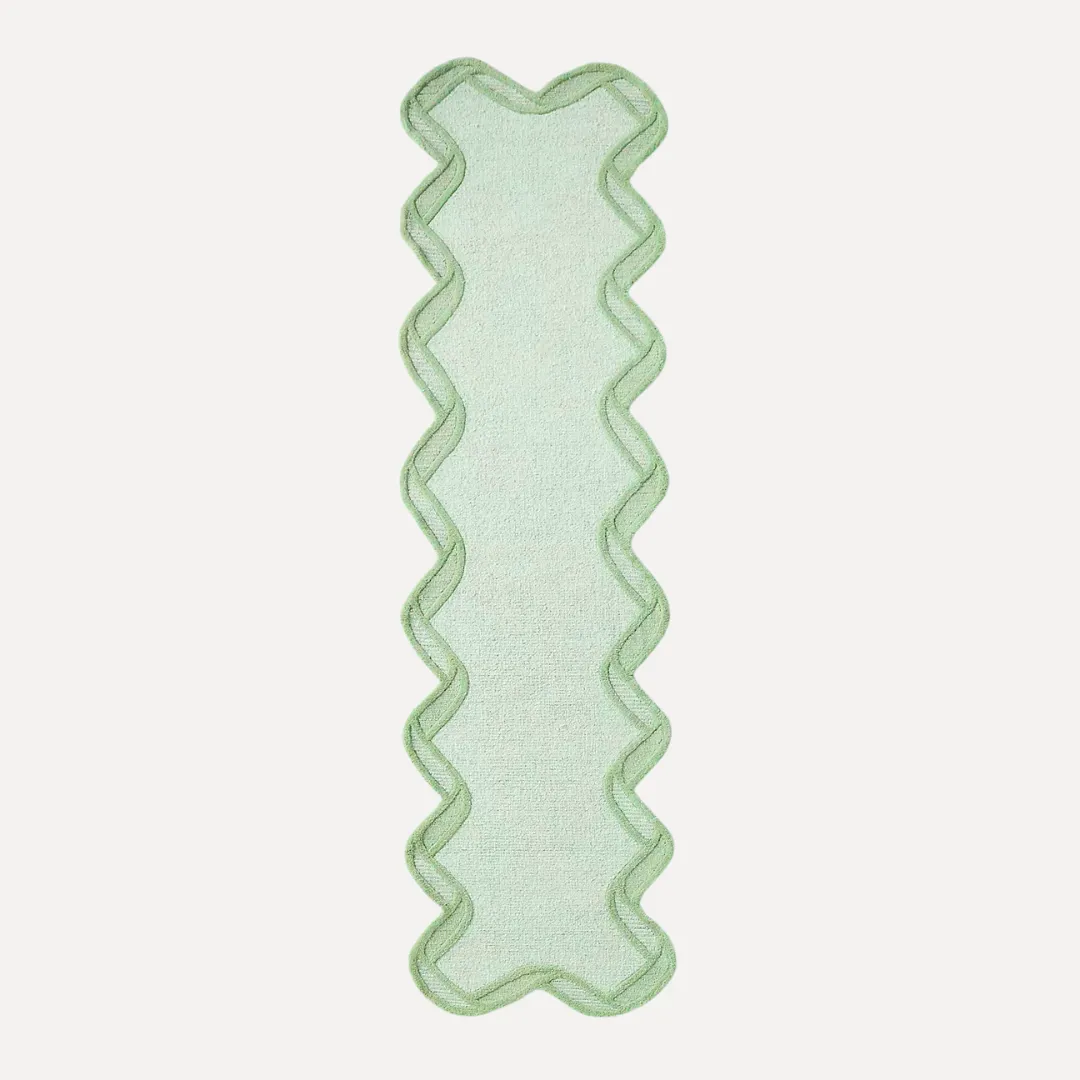 Top-down view of green hand tufted rug in bright room