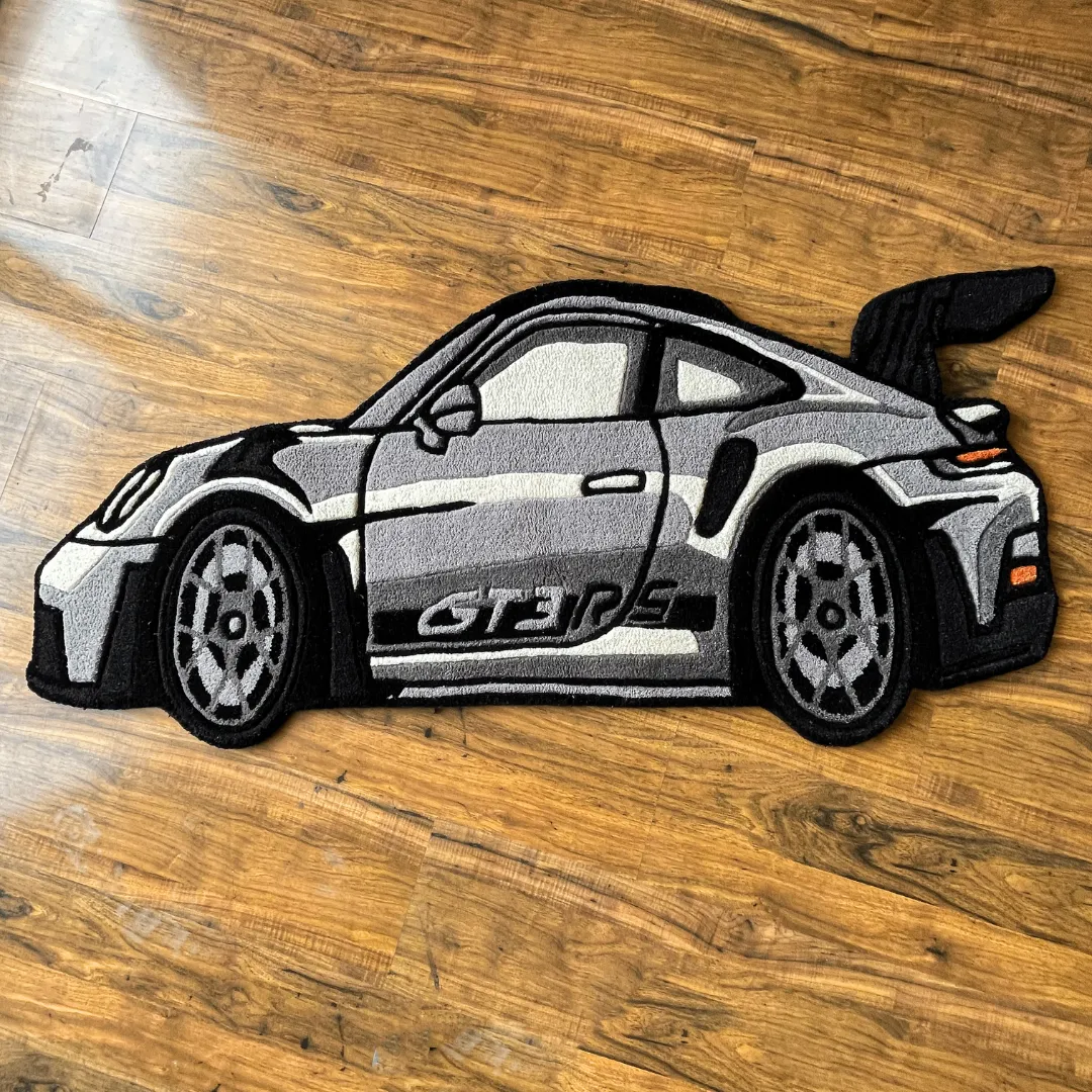 apex race silver gt3rs rug Top down view of the Apex Race rug shaped like a silver Porsche 911 GT3 RS sports car, featuring detailed black accents, a large rear wing, and side branding.