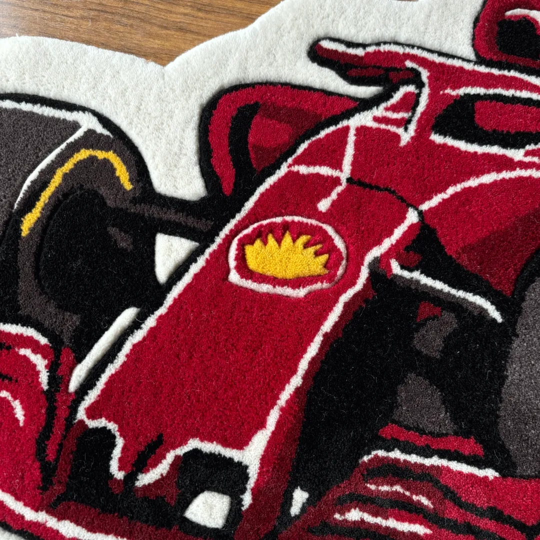 victory drive f1 rug nose detail Close-up detail of the Victory Drive rug, showcasing the plush tufted texture of the red car's front nose and the yellow shield logo.