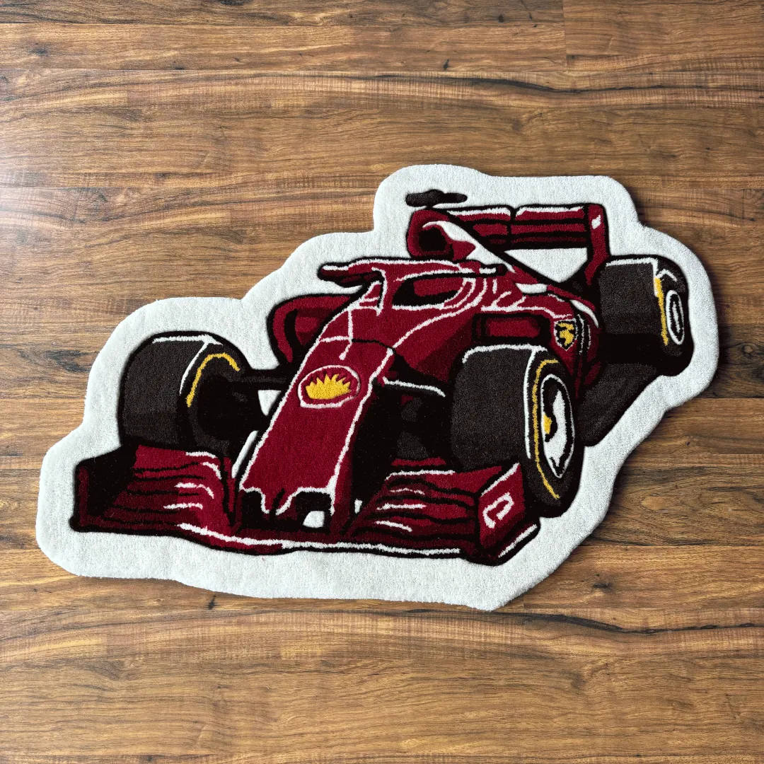 victory drive red race car shaped rug Top down view of the Victory Drive rug featuring a unique die-cut shape illustrating a red Formula 1 race car with black tires and white accents.