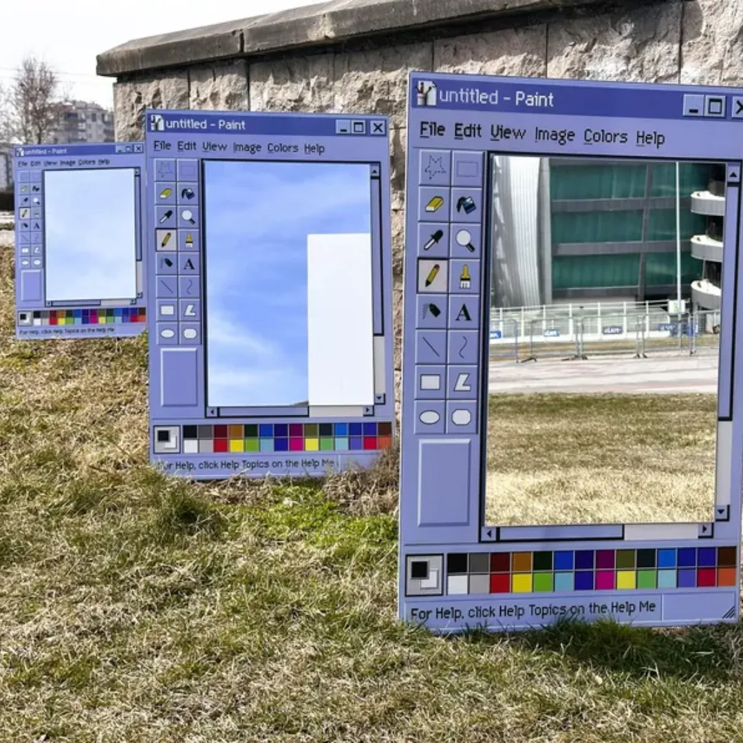 retro window paint app mirror group display A group of multiple retro window mirrors styled as computer paint applications, arranged on a grassy hillside outdoors.