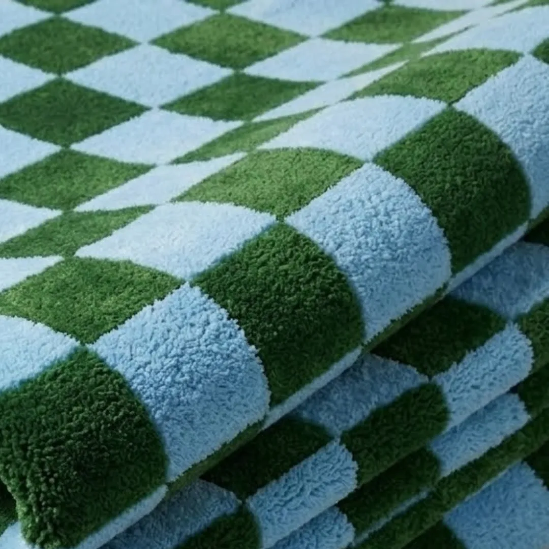 sage check geometric wool area rug texture close up A macro close-up of the folded Sage Check rug, focusing on the dense, tufted wool pile and the crisp, alternating green and blue checkerboard construction.