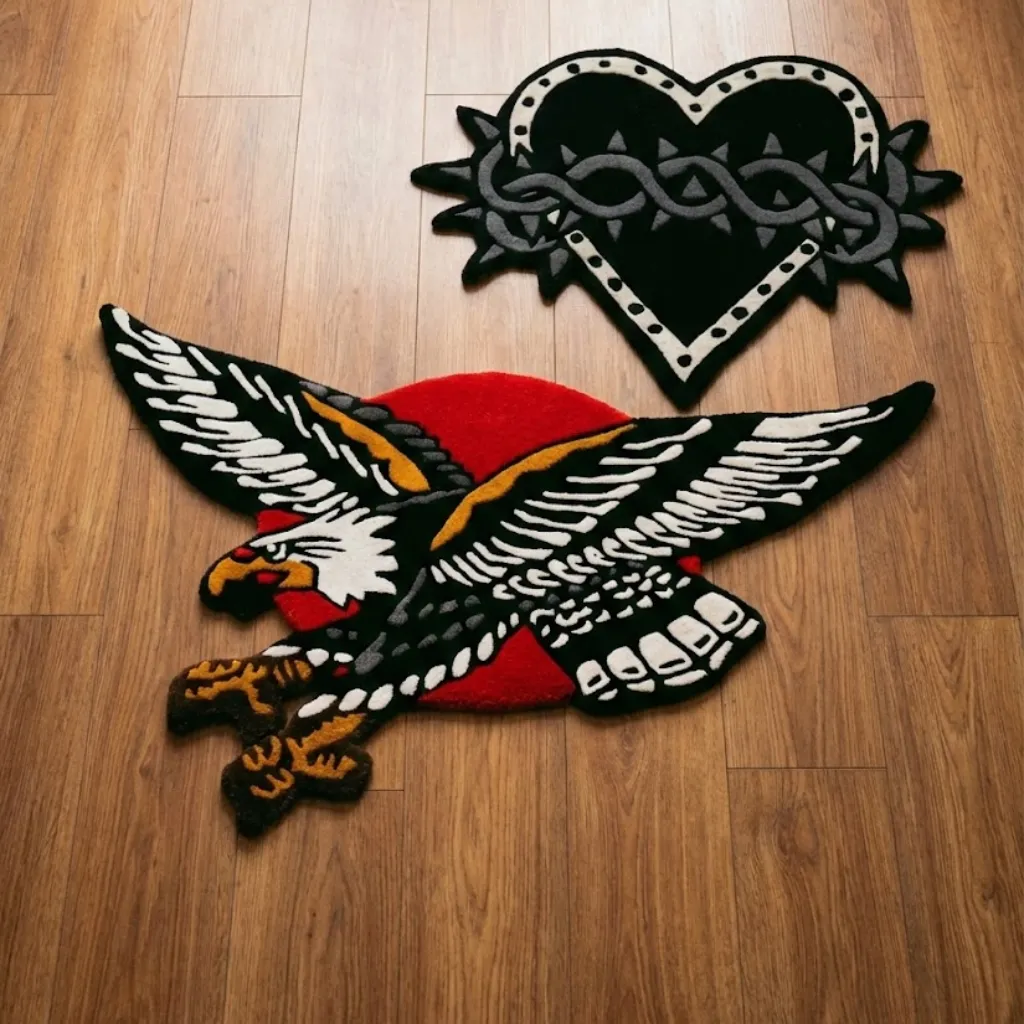 American Traditional Eagle And Heart Tattoo Rugs Top down view of two hand tufted tattoo style rugs: a flying American eagle against a red sun and a black heart with thorns, displaying classic old school aesthetics.