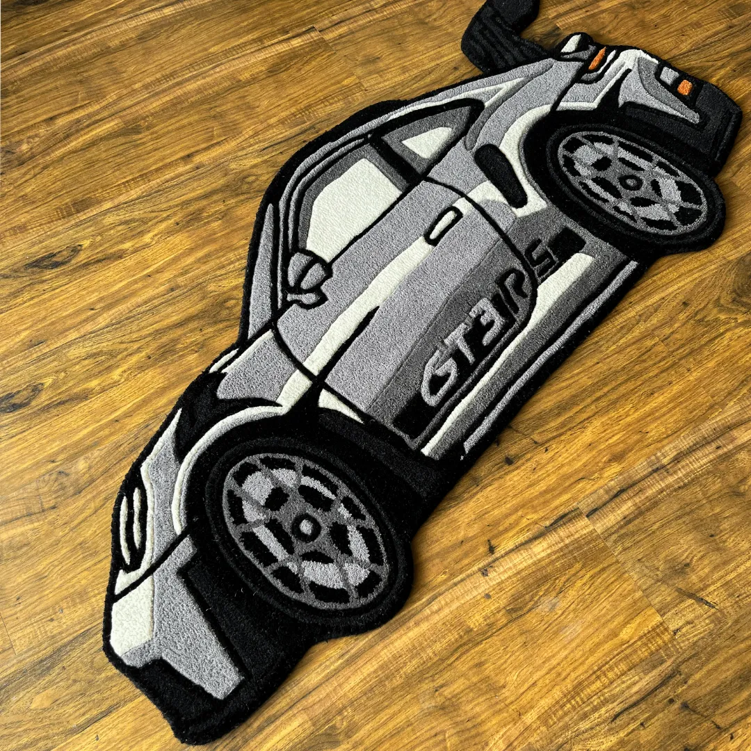 apex race rug sports car shaped decor erspective view of the Apex Race rug placed on a wooden floor, highlighting the die-cut shape and the plush tufted texture of the grey high-performance car design.