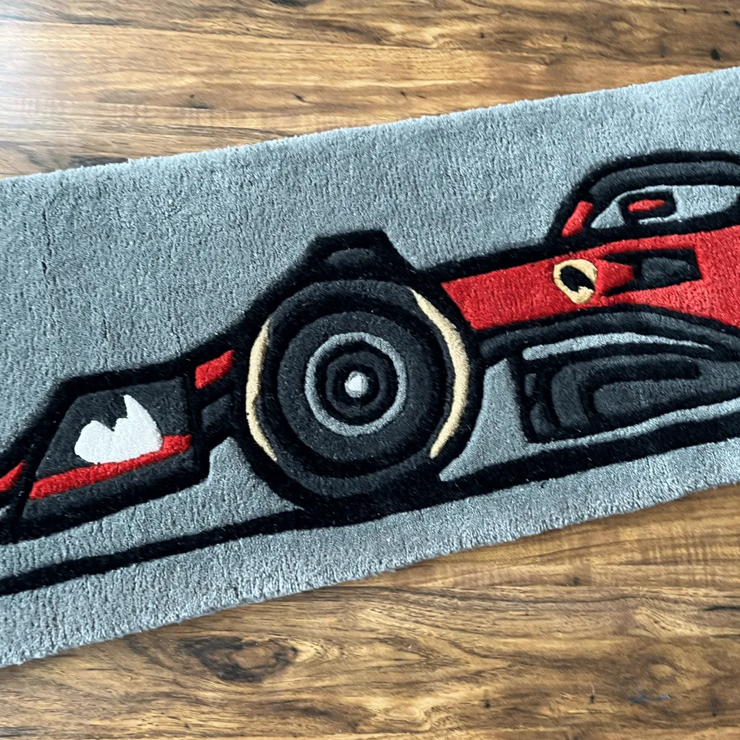 asphalt aura f1 car rug wheel texture Detailed close-up of the Asphalt Aura rug showing the black rear tire and aerodynamic side panels of the red race car design.