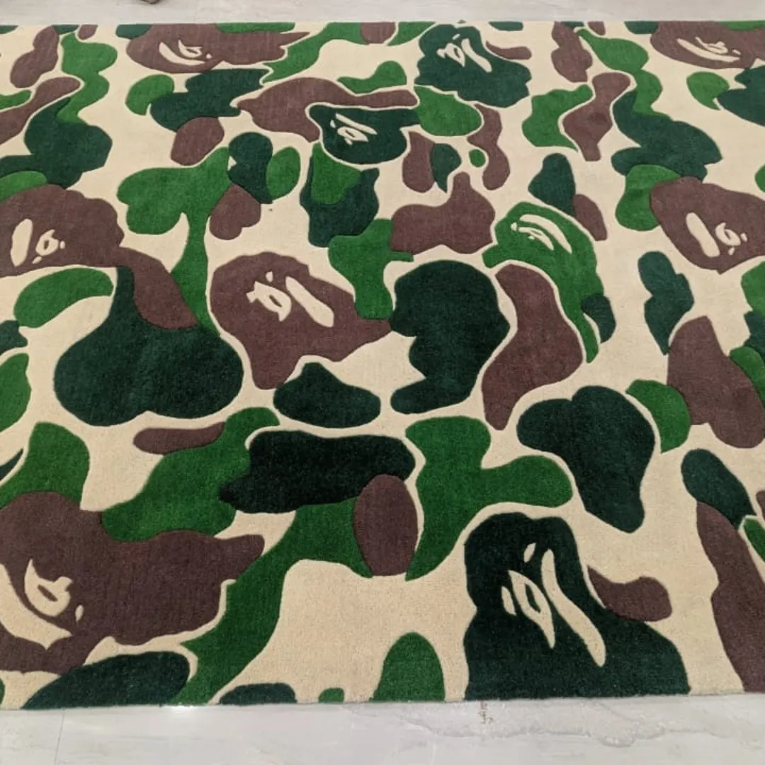shadowfield camo terrain rug detail Close-up angled view of the Shadowfield Camo Terrain rug on a light tile floor, highlighting the plush hand-tufted wool texture and the sharp definition between the green, brown, and cream camouflage pattern.