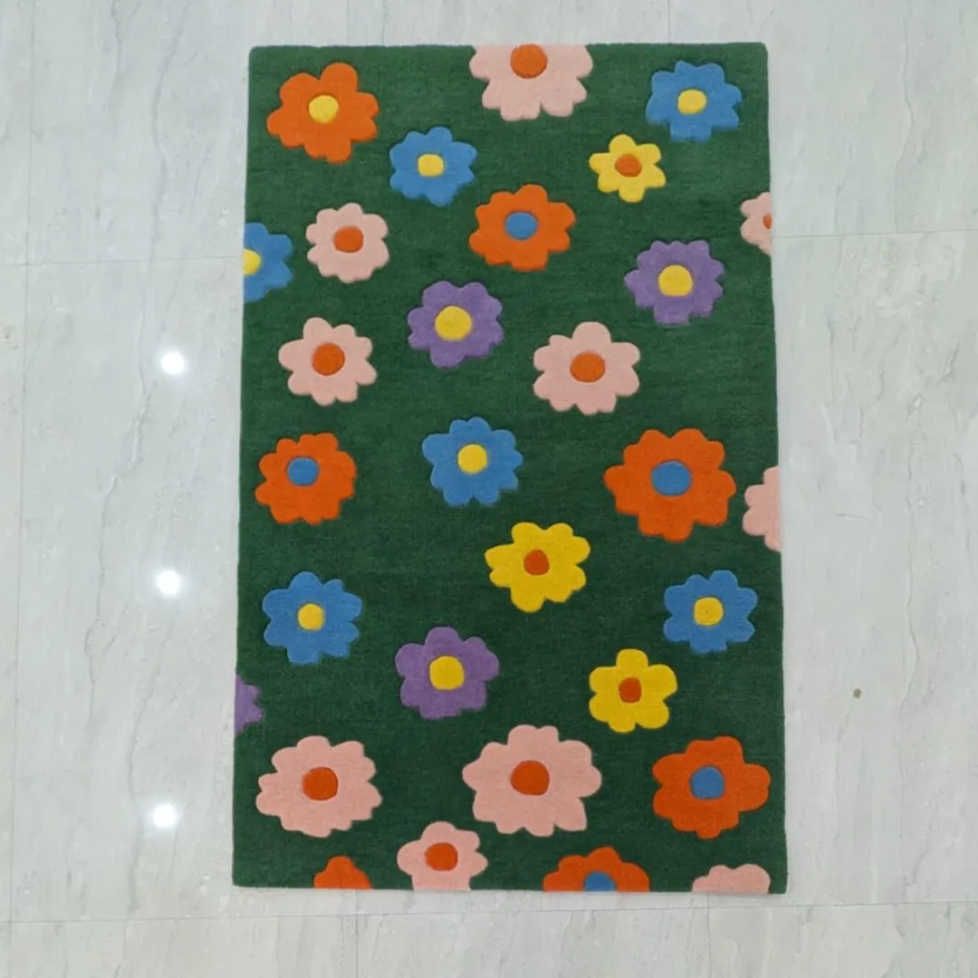 daisy bloom rug full overhead view Full overhead shot of the rectangular Daisy Bloom Rug laid completely flat on a light grey tiled floor. The design showcases a repeating pattern of bright, multicolored tufted daisy flowers on a solid dark green background.