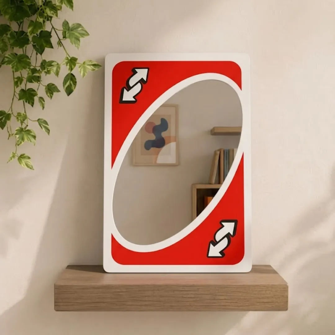 flip frame reverse card mirror wooden shelf display Angled view of the Flip Frame mirror, featuring a red reverse card graphic, positioned on a wooden floating shelf against a wall with hanging ivy.