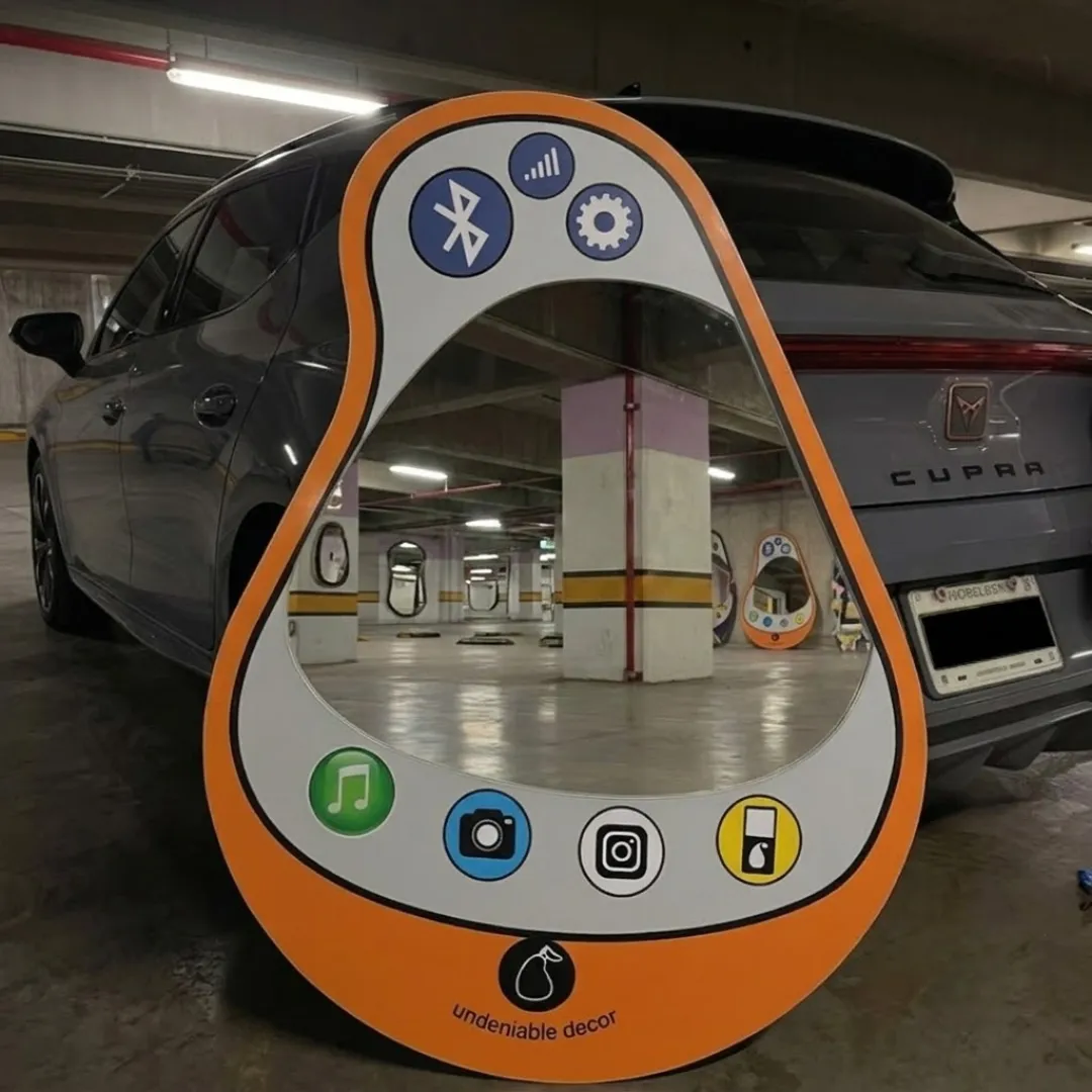 pear pop phone mirror urban garage lifestyle Wide angle lifestyle shot of the bright orange Pear Pop Phone Mirror resting on the floor of a concrete underground parking garage, reflecting the interior columns and a grey vehicle.