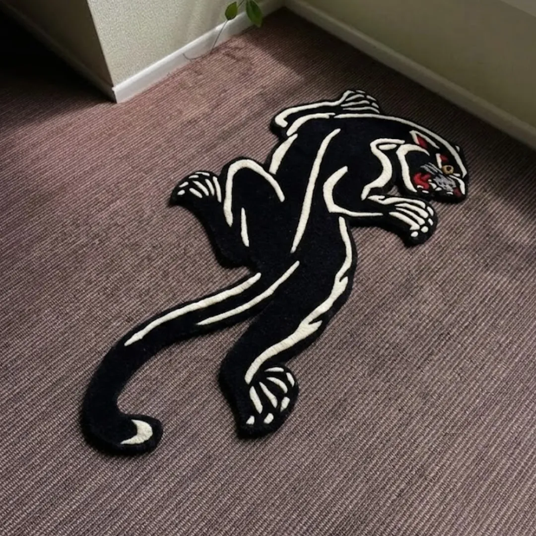 shadow prowl panther shaped area rug product shot A top-down studio photograph of the Shadow Prowl area rug, featuring a striking hand-tufted black panther silhouette with white skeletal-style accents on a textured floor.