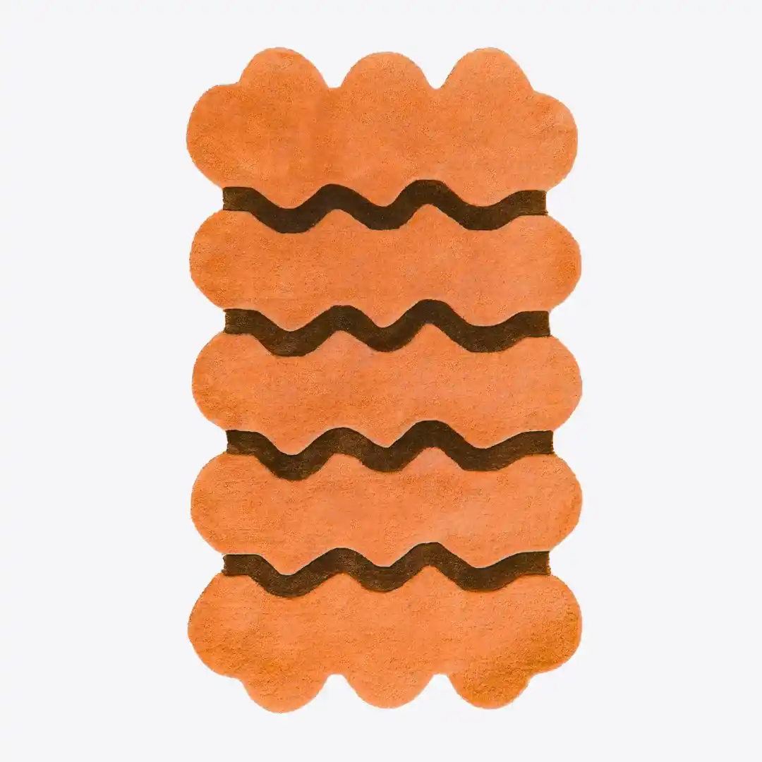 Hand-tufted scallop edge solid orange wool rug displayed in a modern living room setting.