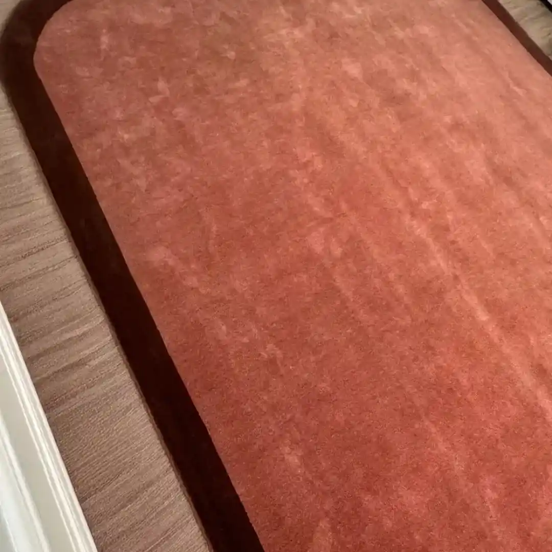 Vacuuming and caring for the Solid Rust Border Hand Tufted Rug, demonstrating easy maintenance.