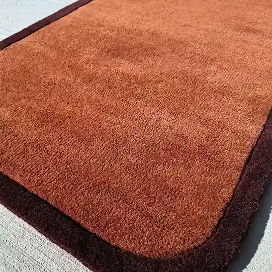 Close-up view of the Solid Rust Border Rug’s hand-tufted texture, showcasing the luxurious wool material.