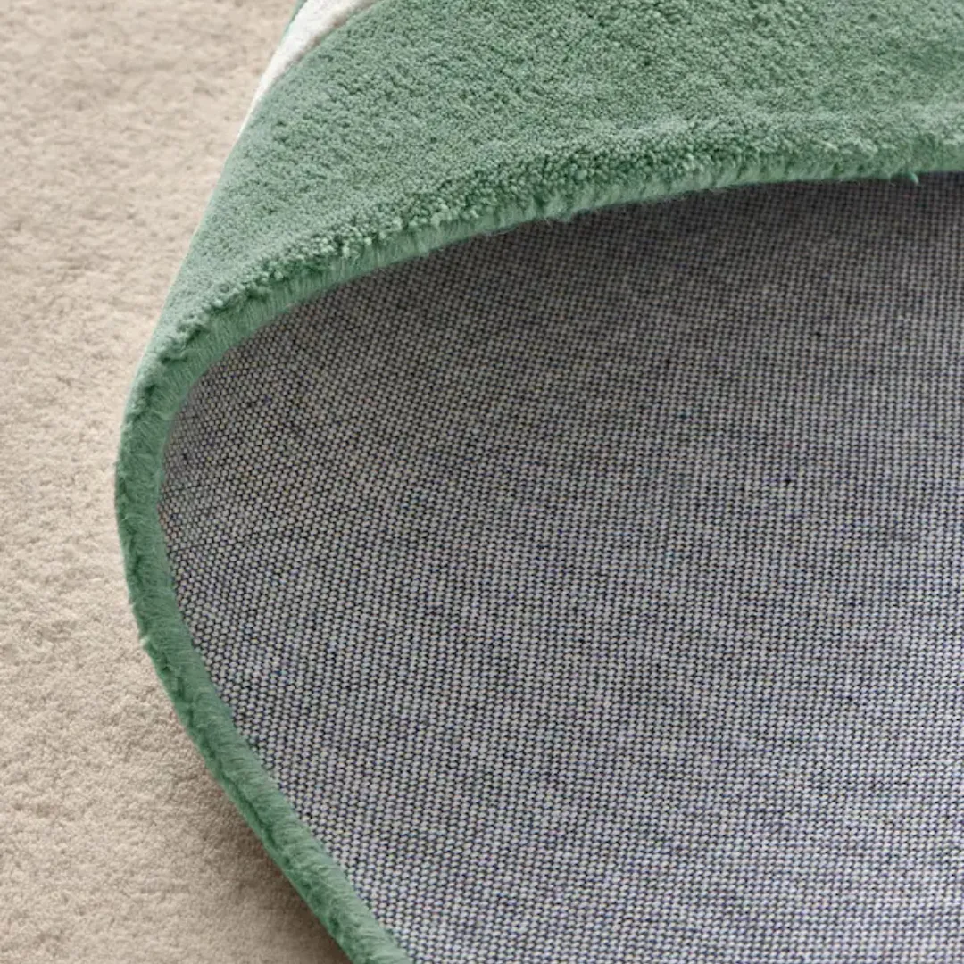 Top view of rectangular rug with green border and soft scalloped design