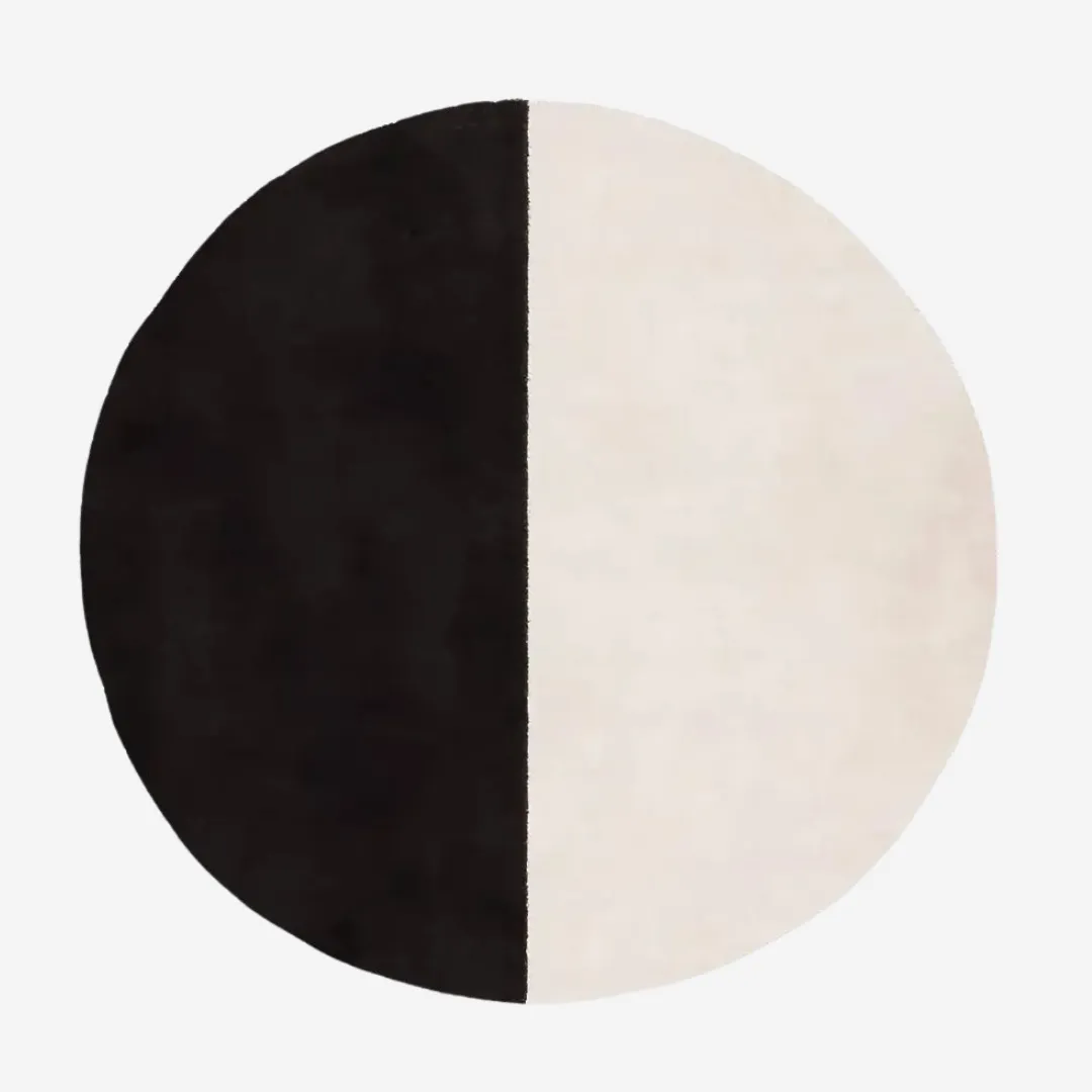 Half black and white round rug on wooden floor