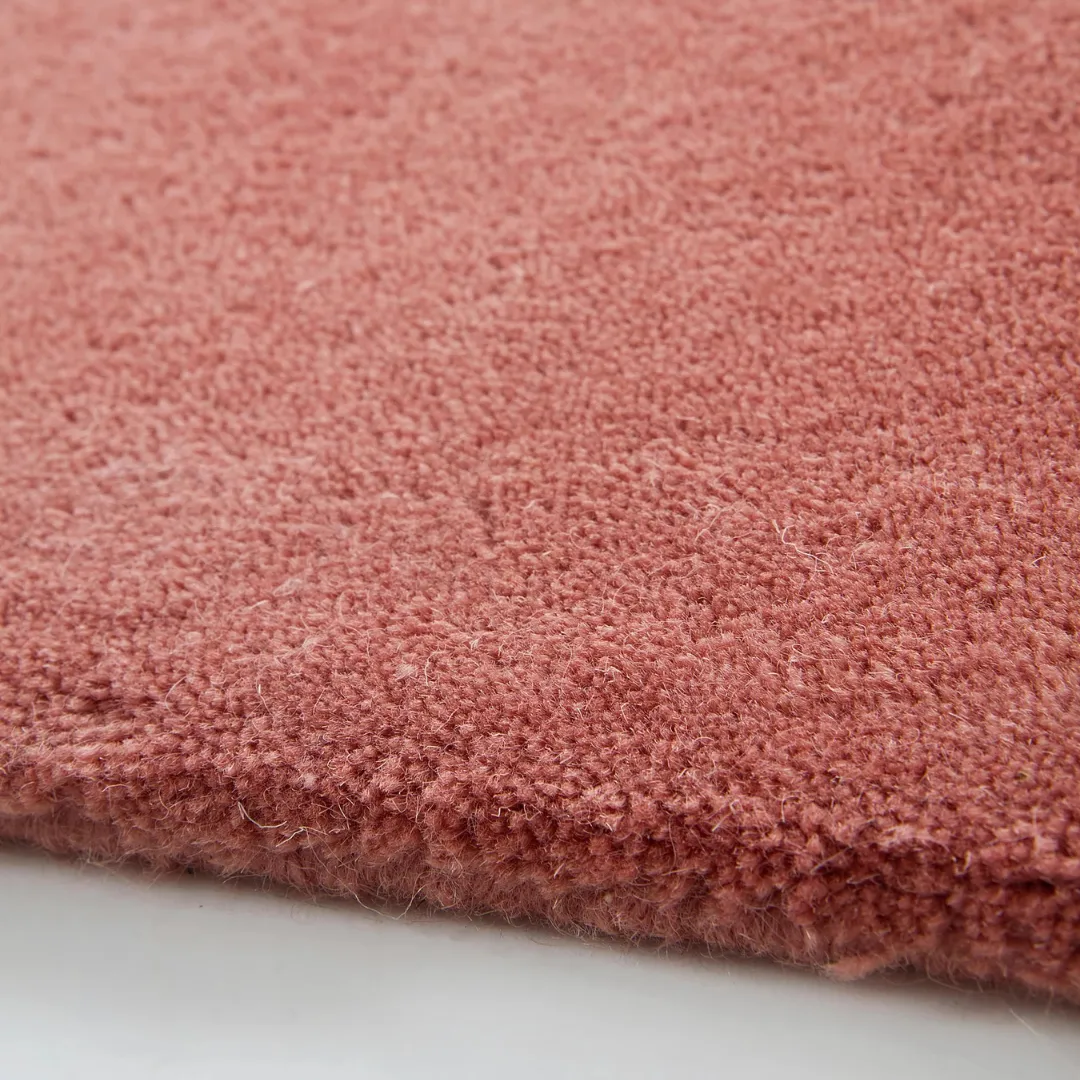 Dusty rose red area rug on wooden floor