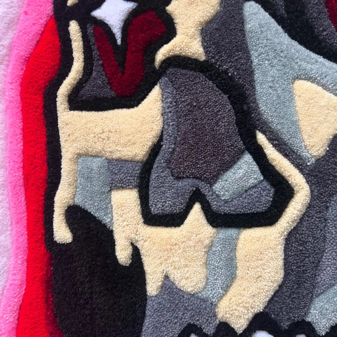 Hand tufted Psychedelic skull-shaped rug with red eyes, camo shading, and a swirling red-pink tongue design close up.