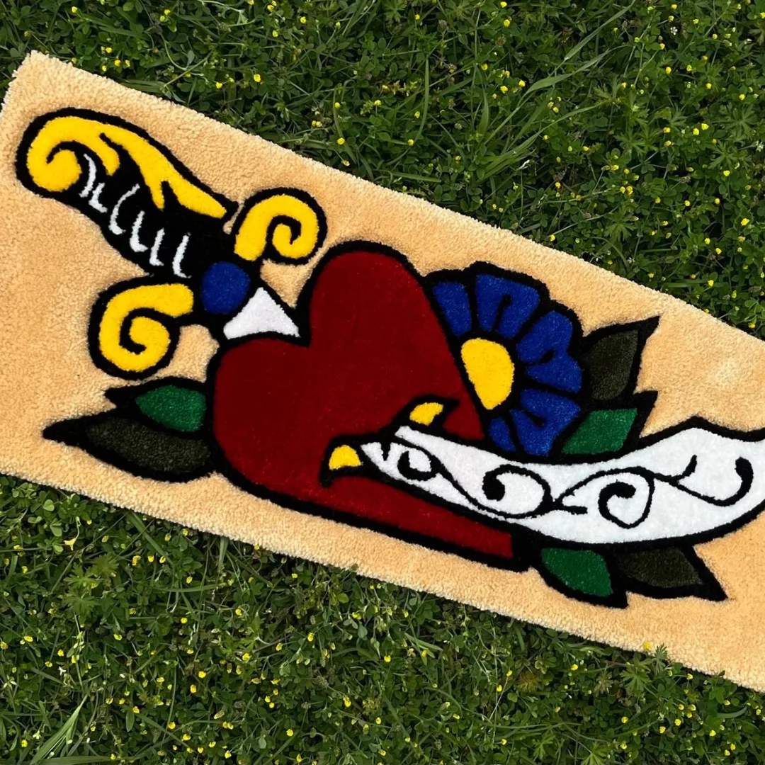 Hand-tufted rug with a red heart, dagger, flower, and banner in classic tattoo flash art style