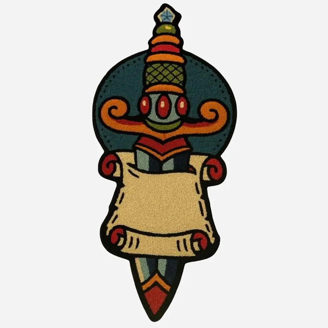 Tattoo-inspired hand tufted rug featuring a colorful dagger piercing through a scroll, designed in teal, red, beige, and gold on a white background.