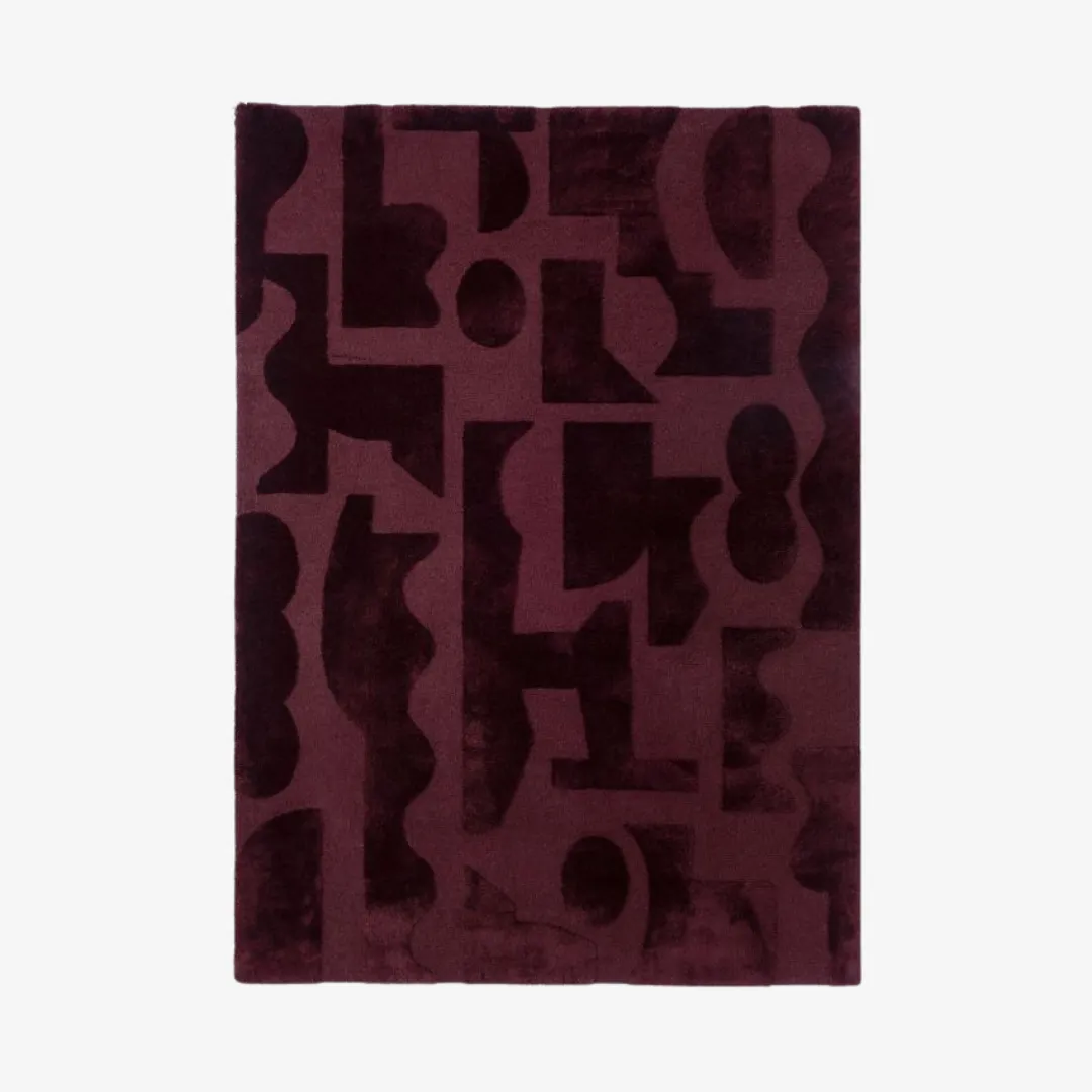 Bold abstract geometric area rug in rich maroon.