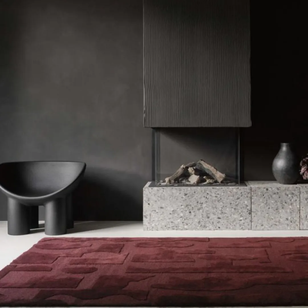 Maroon area rug with large geometric shapes in abstract design.