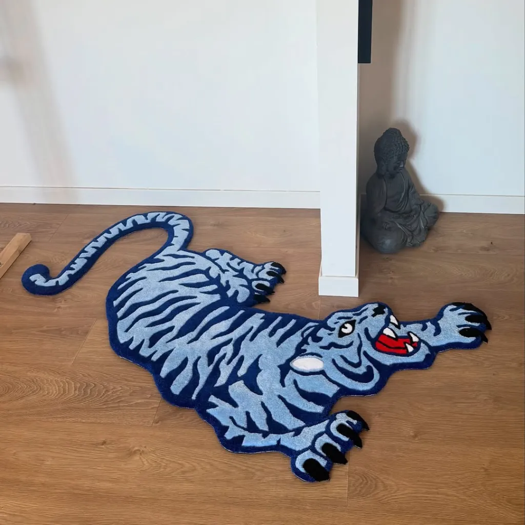 Cool Fang Inked Blue Tiger Rug Room Decor High angle view of the custom shaped Cool Fang rug featuring a stylized blue tiger design displayed on a wooden floor next to a Buddha statue.