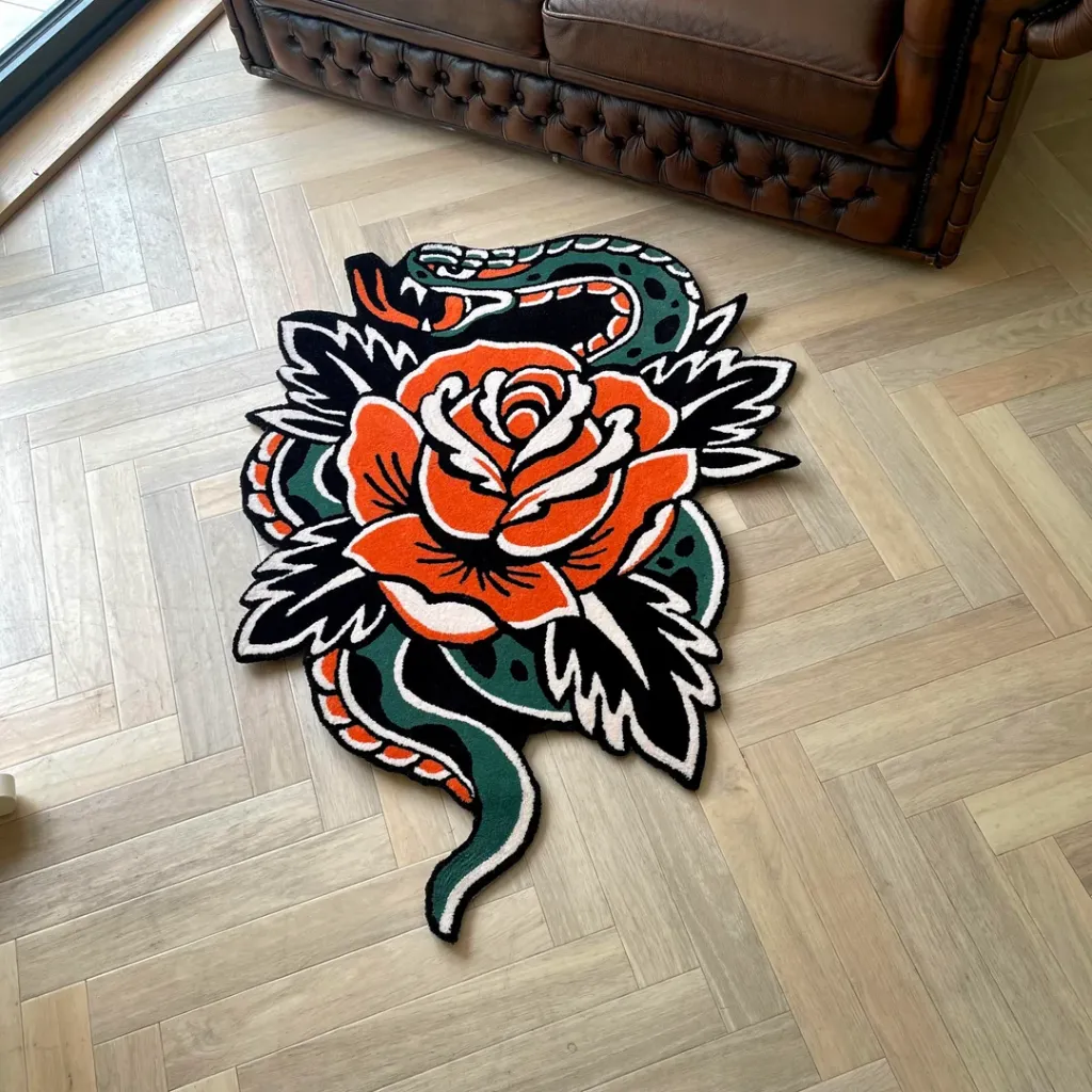 Snake Rose Traditional Tattoo Rug Living Room High angle shot of the Snake Rose Traditional rug placed on a herringbone wooden floor next to a leather sofa, showcasing the bold old school tattoo aesthetic and vibrant colors.