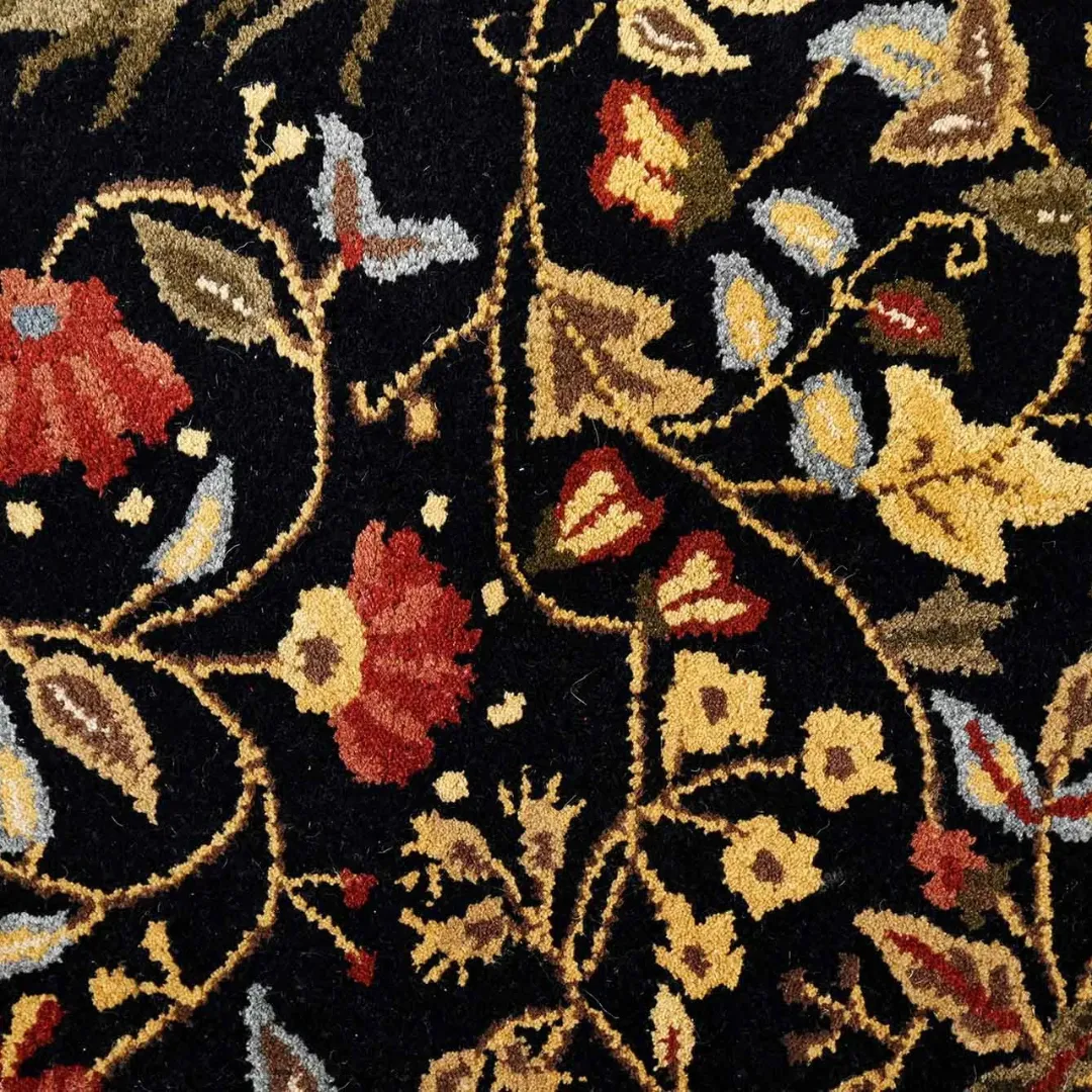 Wool floral rug with red, green, and gold accents on dark background