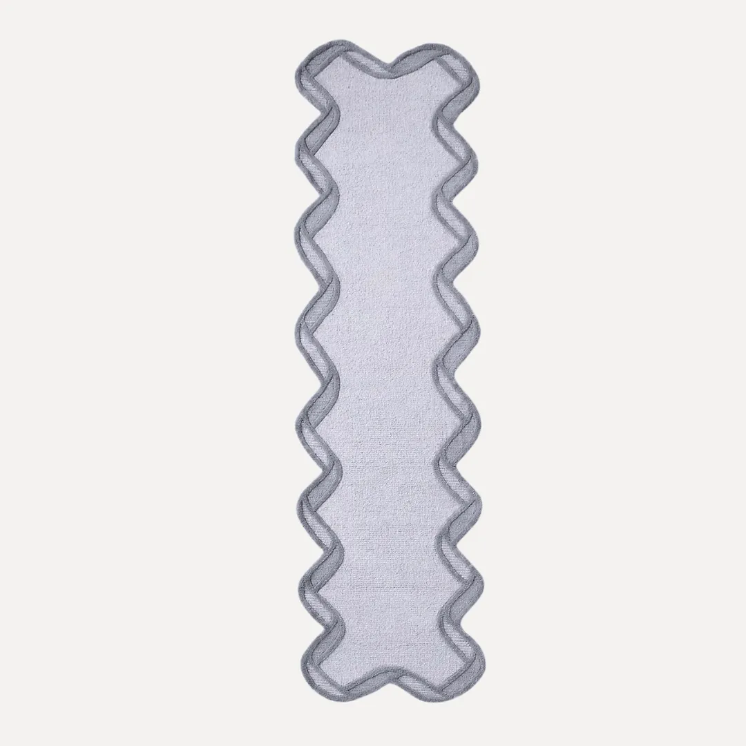 Close-up of scallop border detail on gray hand tufted rug