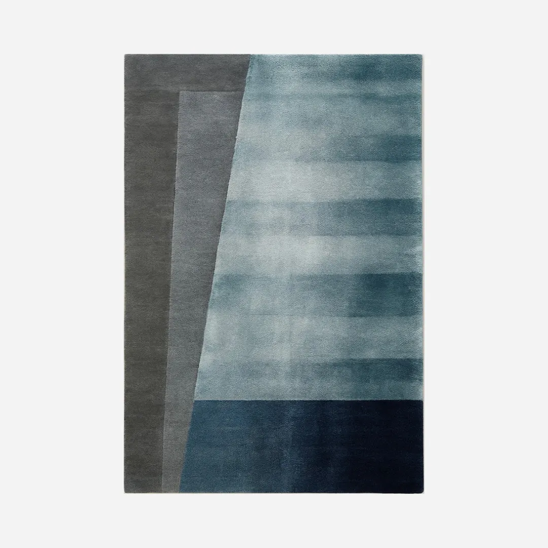 Modern area rug in overlapping shades of blue with clean lines and soft texture.