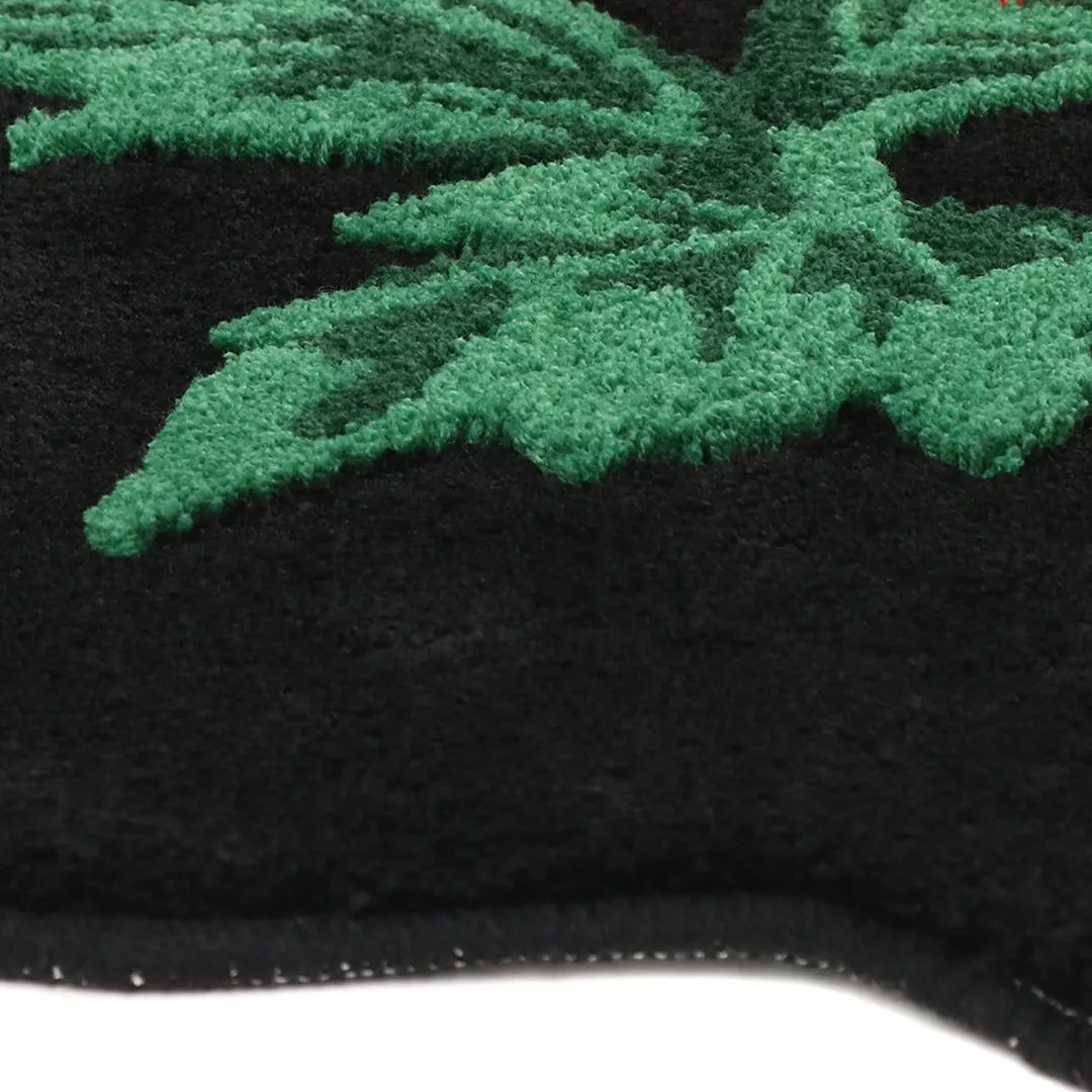 Black rug in the shape of a floral with red blooming flower and green leaves, hand-tufted for bold and thoughtful decor