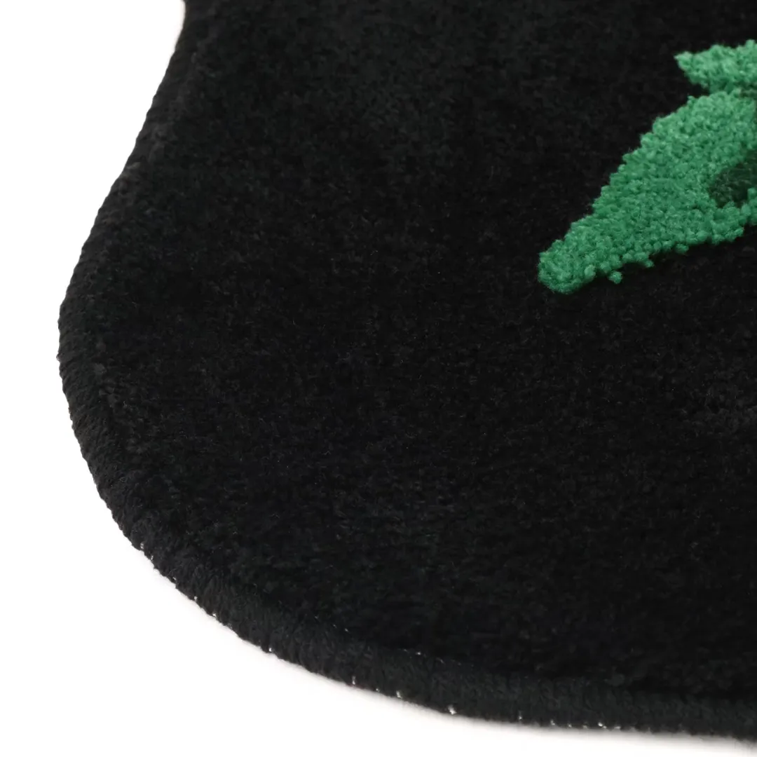 Black rug in the shape of a flower with red blooming flower and green leaves, hand-tufted for bold and thoughtful decor